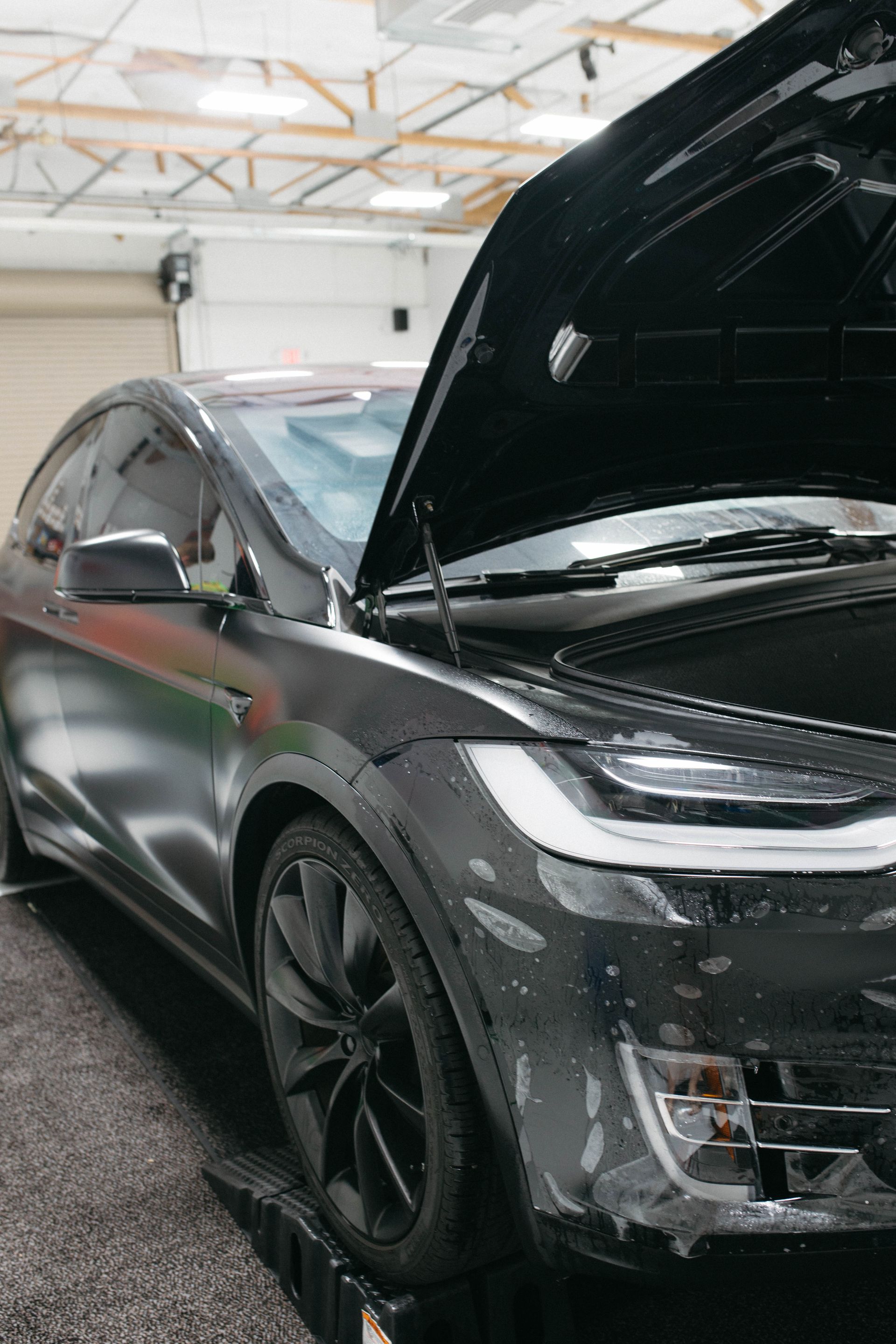 a tesla is parked in a garage with the hood open