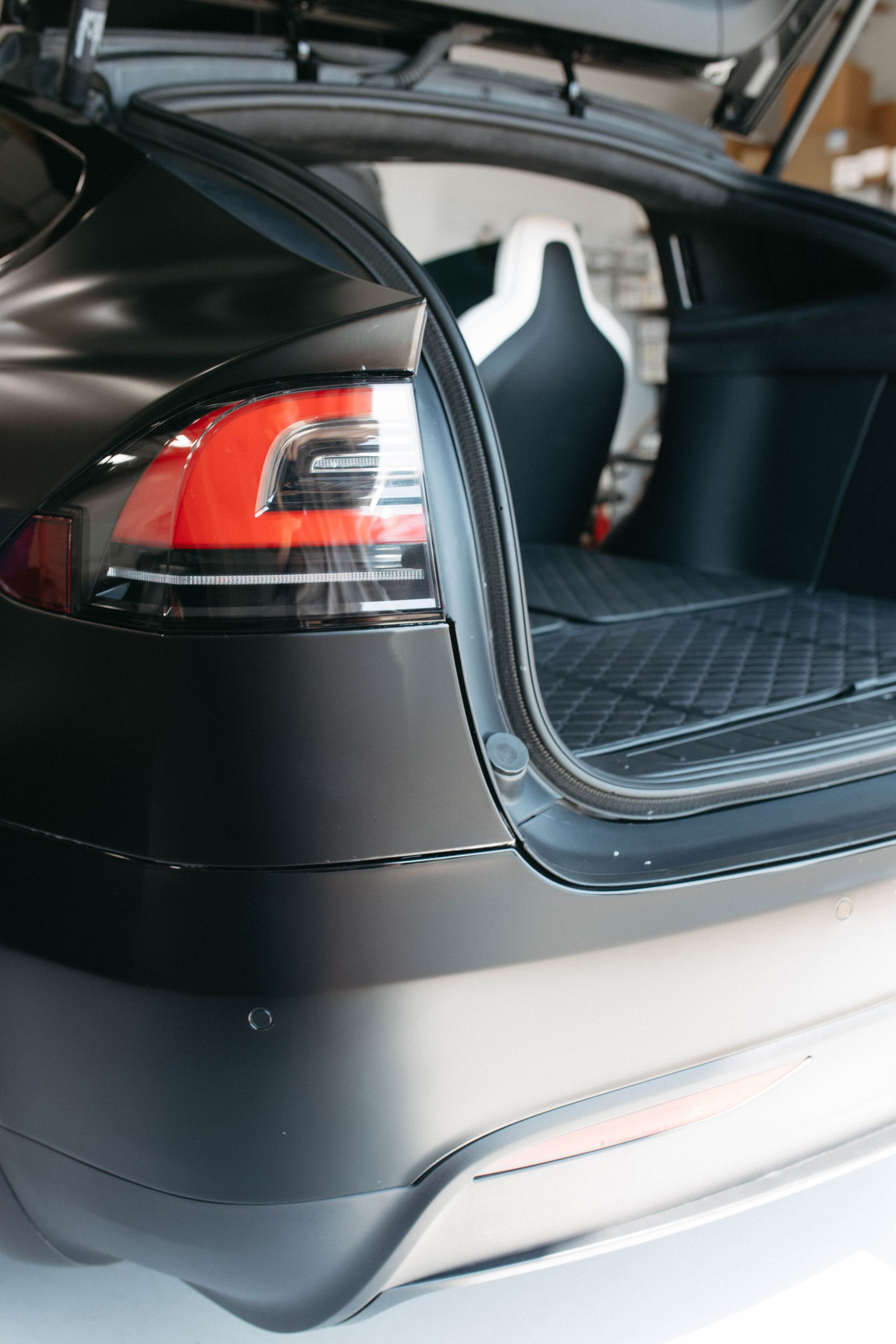 the back of a black tesla with the trunk open