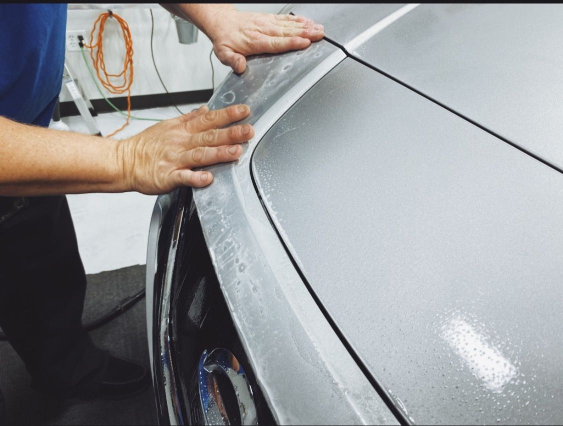 a man in a blue shirt is working on a car