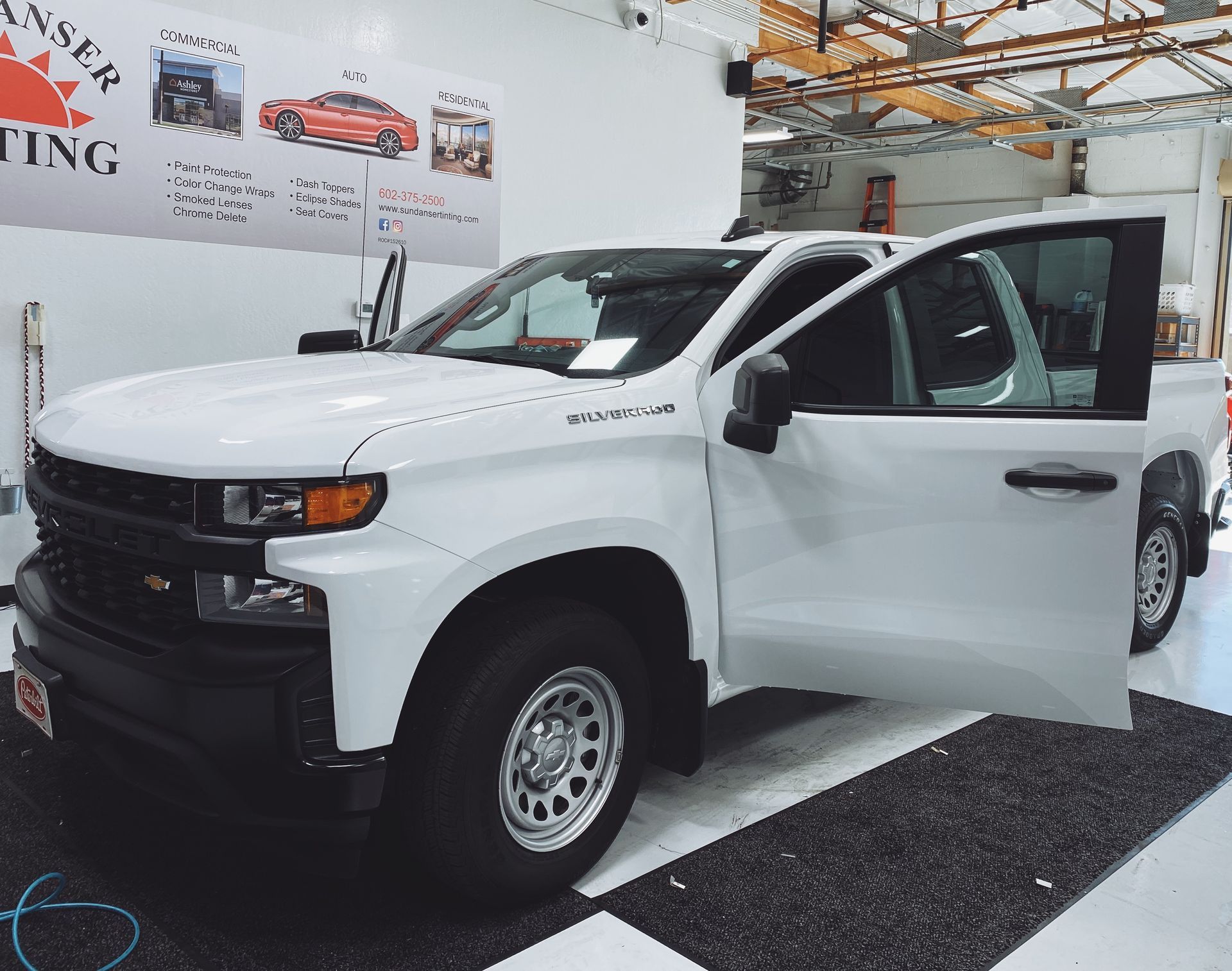 a white truck is parked in a garage with its doors open