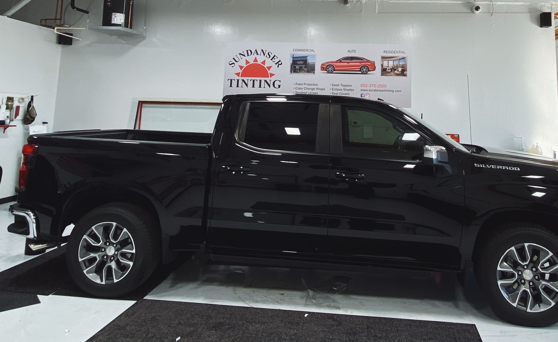 a black truck is parked in a garage next to a sign that says tinting