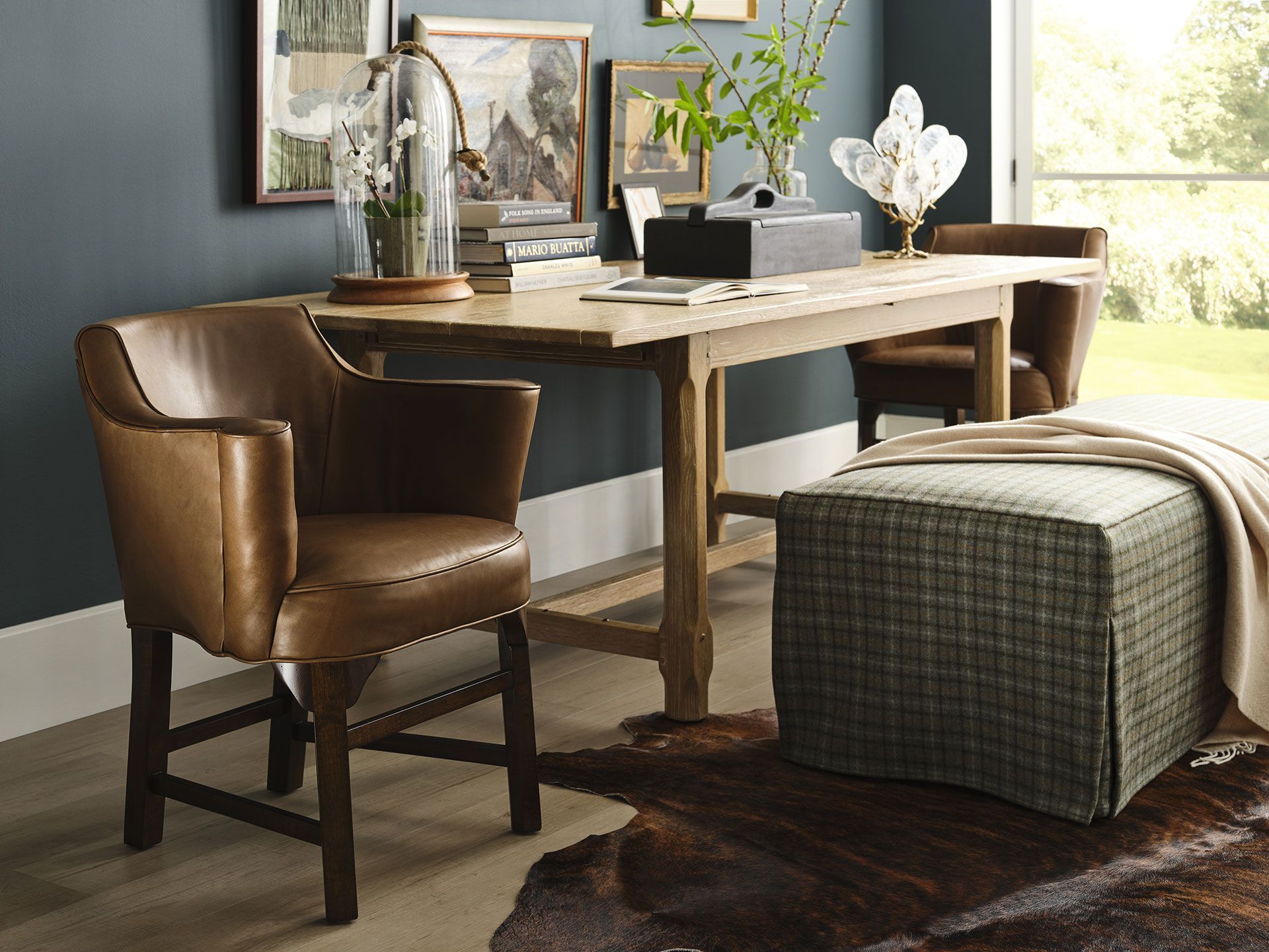 A room with a desk , chair , ottoman and rug