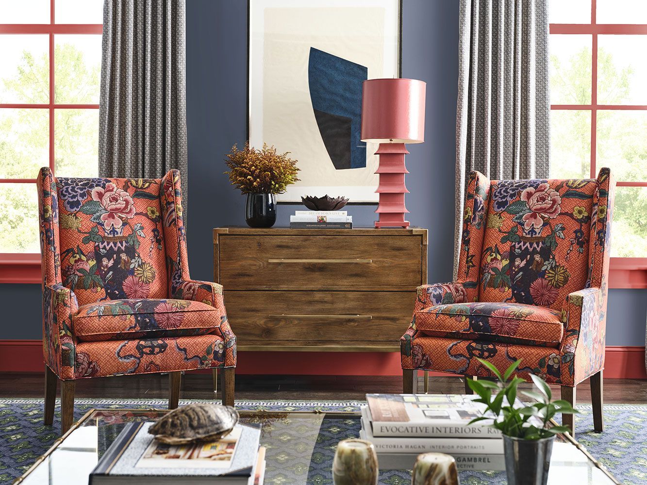 A living room with two chairs , a coffee table , a dresser and a lamp.