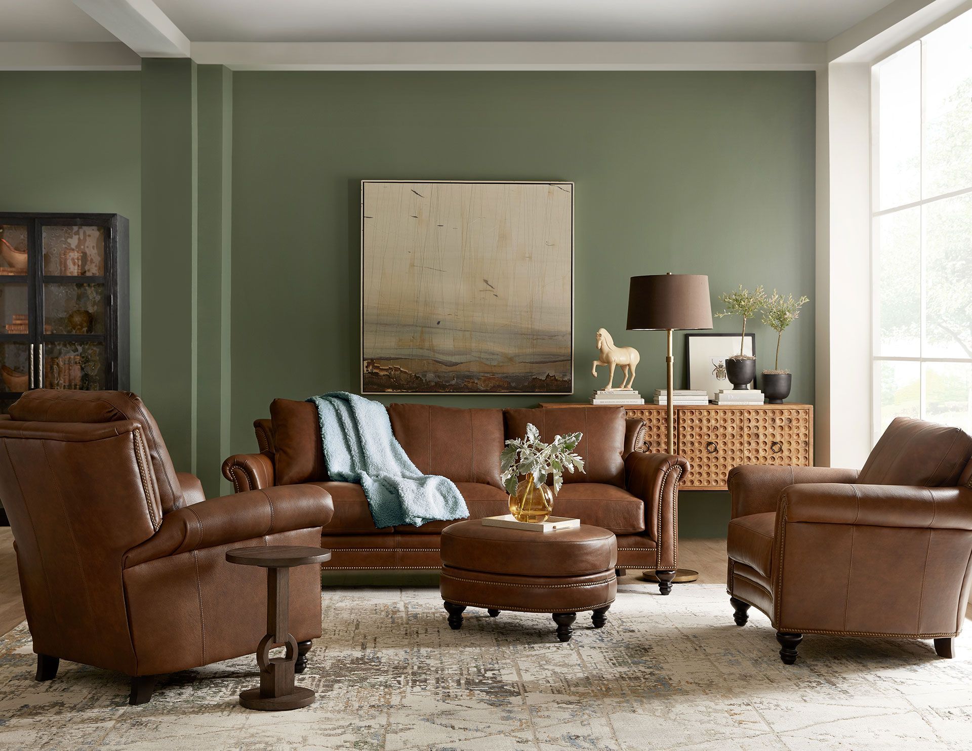 A living room with brown leather furniture and green walls.