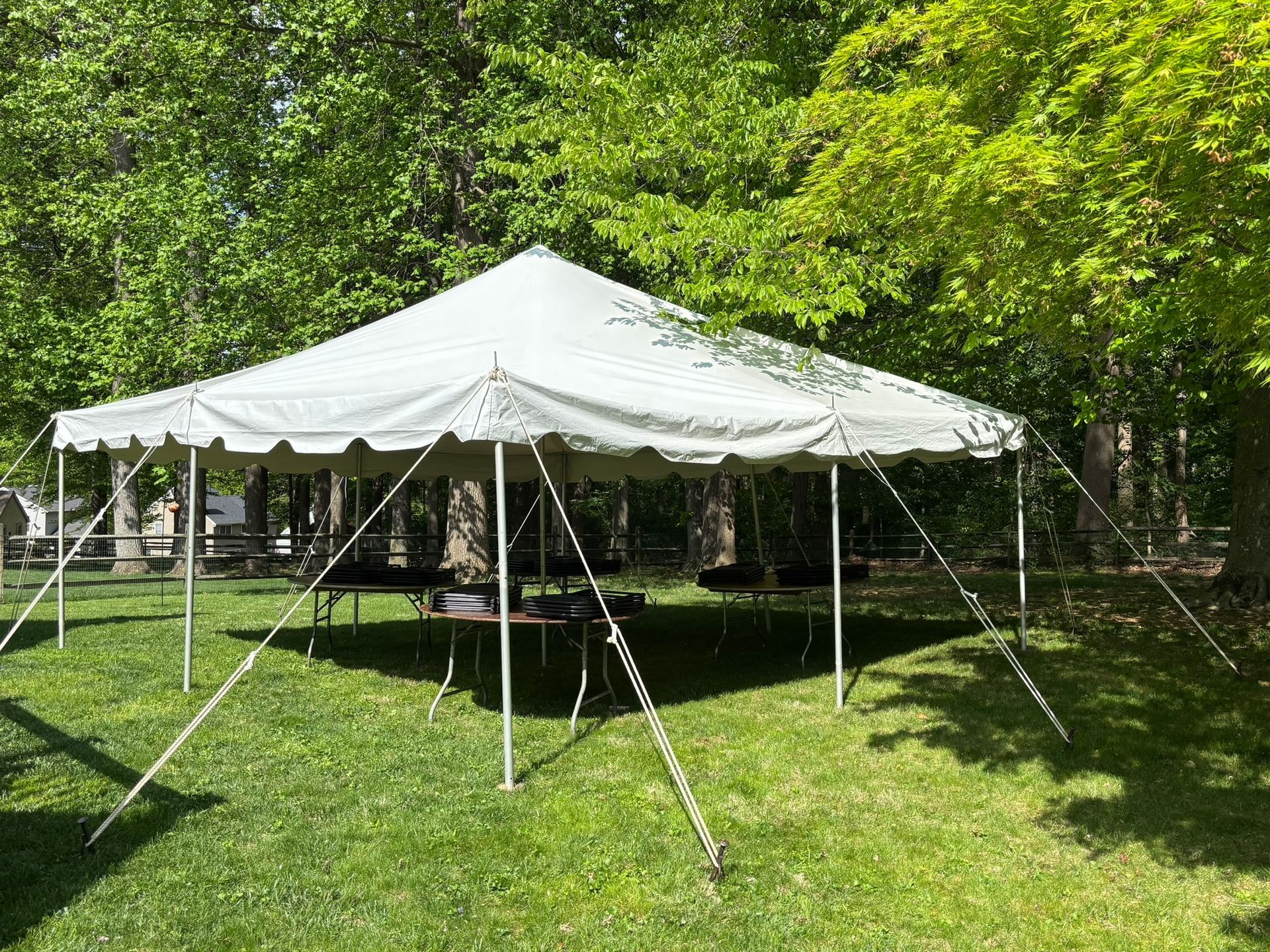 White tent set up on green grass, with trees in the background.