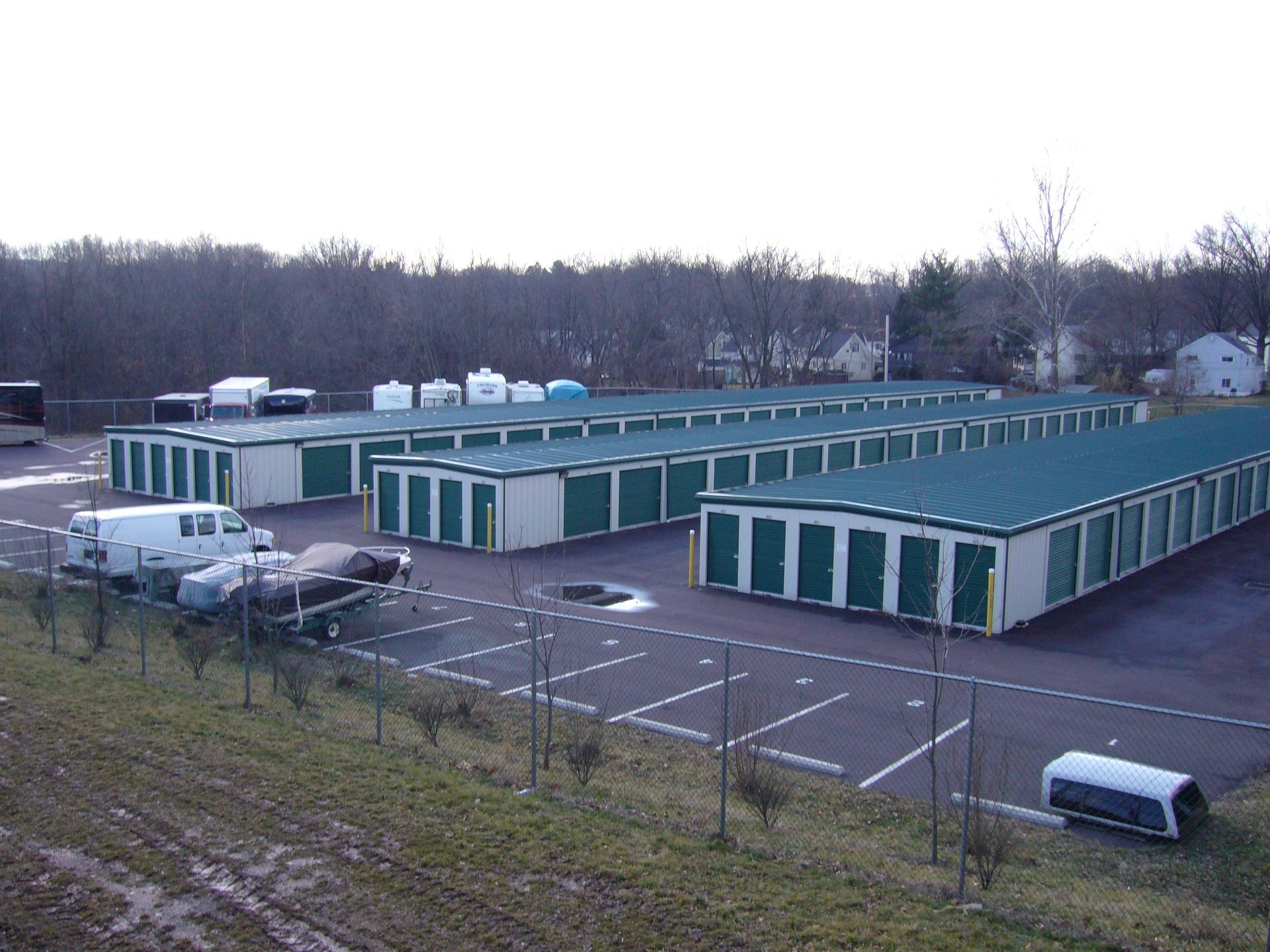 A large storage facility with green roofs and a lot of vehicles parked in front of it.