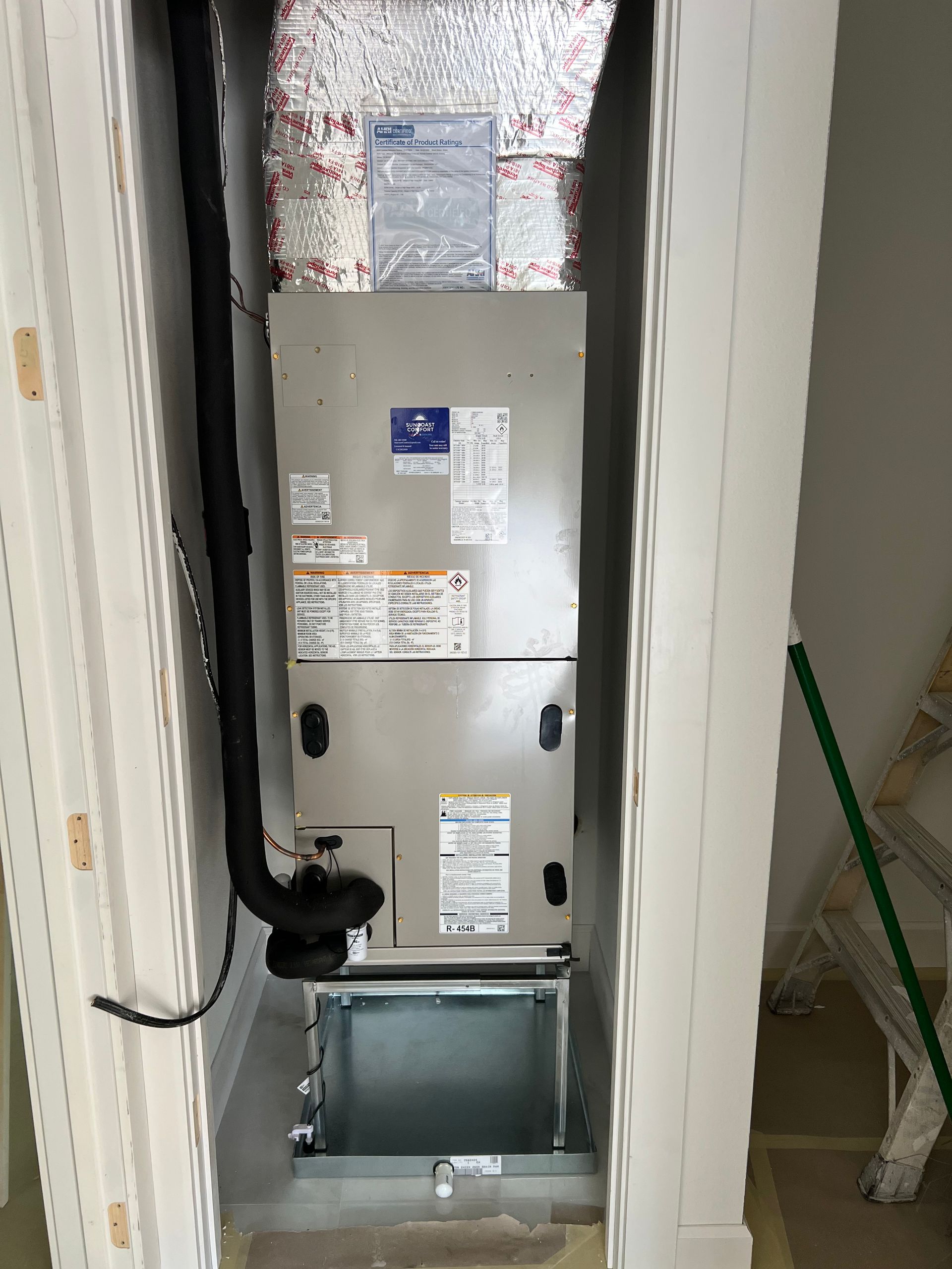 HVAC unit in a white closet. Ductwork, metal box, and silver insulation visible.