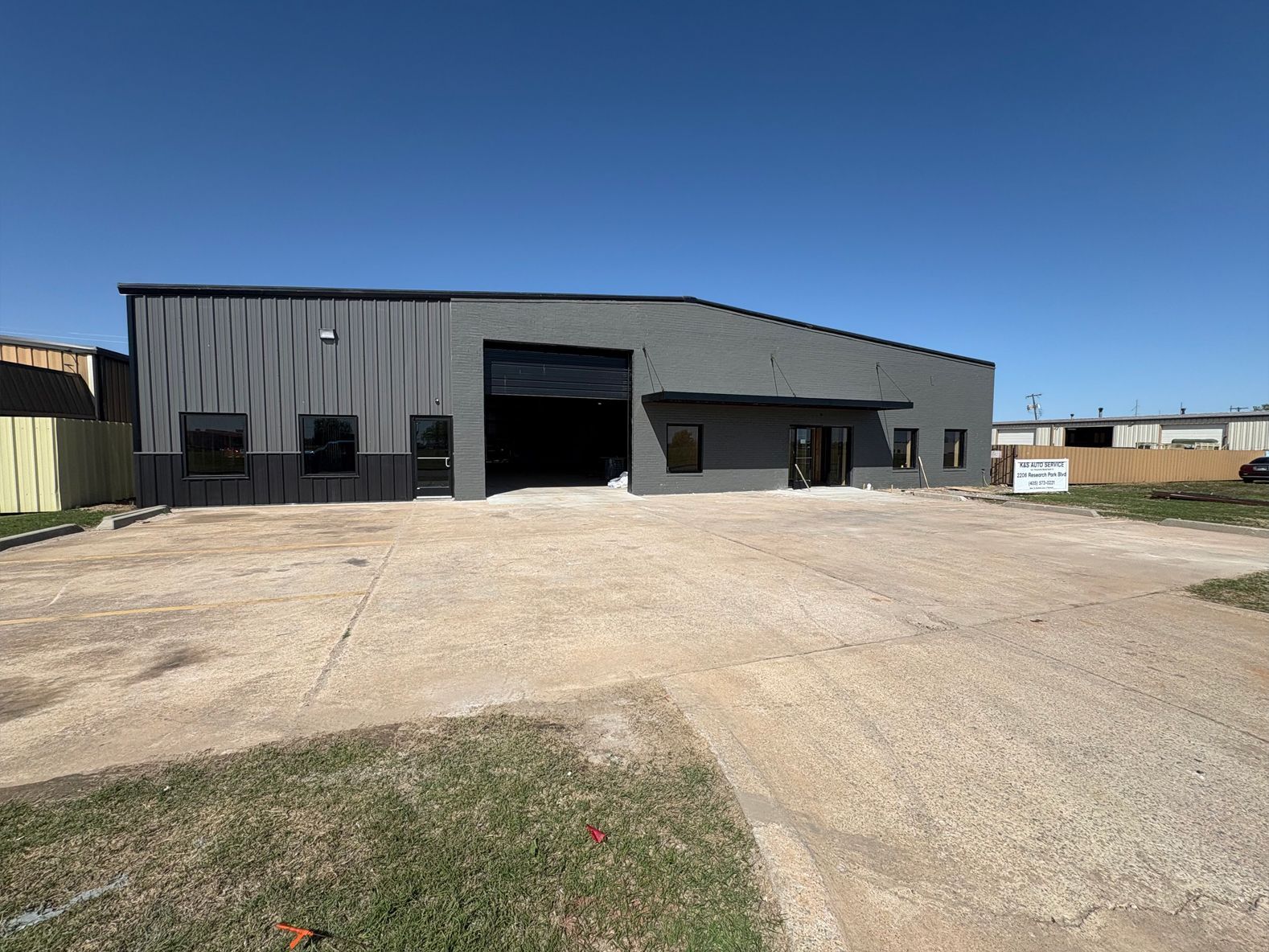 A large building with a lot of windows is sitting on top of a dirt field.