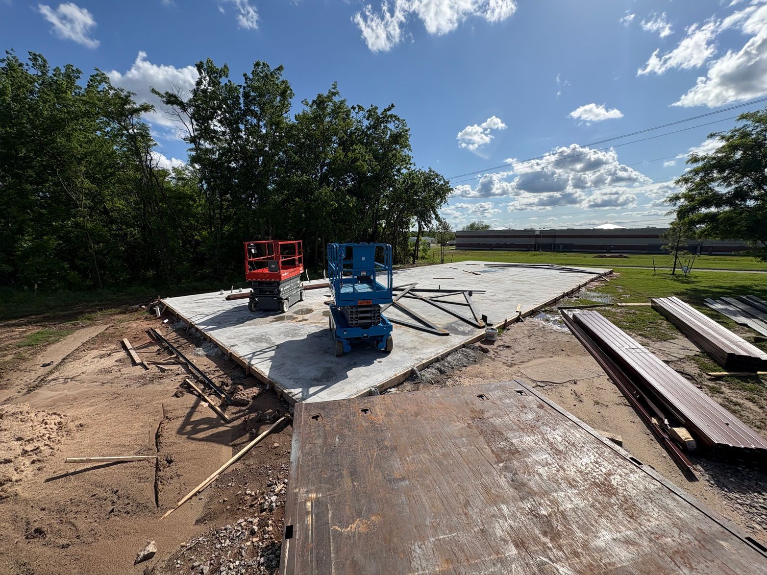 A construction site with a lot of machinery and trees in the background