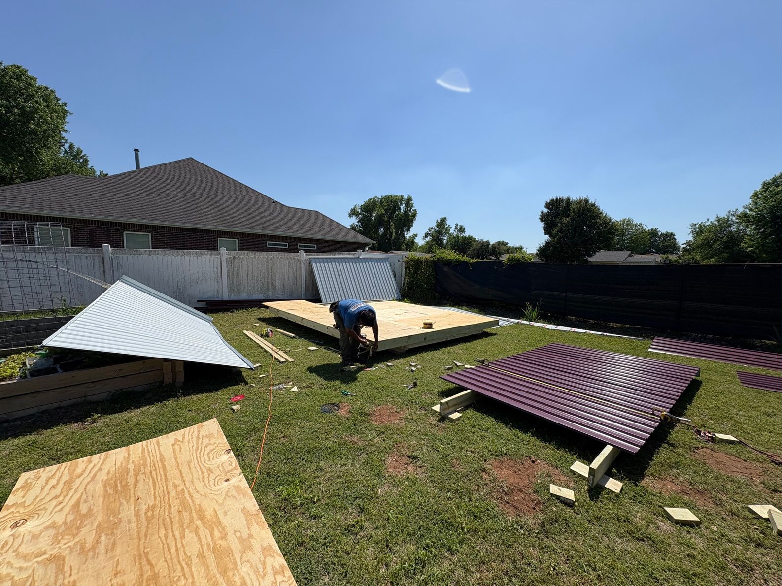 A man is working on a shed in a backyard.