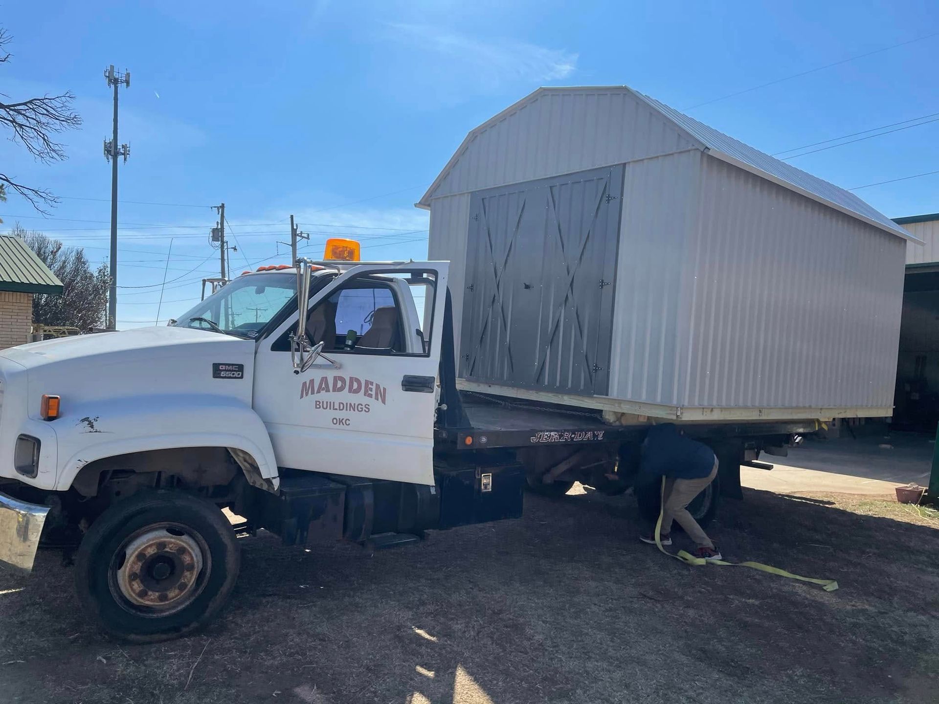 A tow truck is carrying a shed on the back of it.