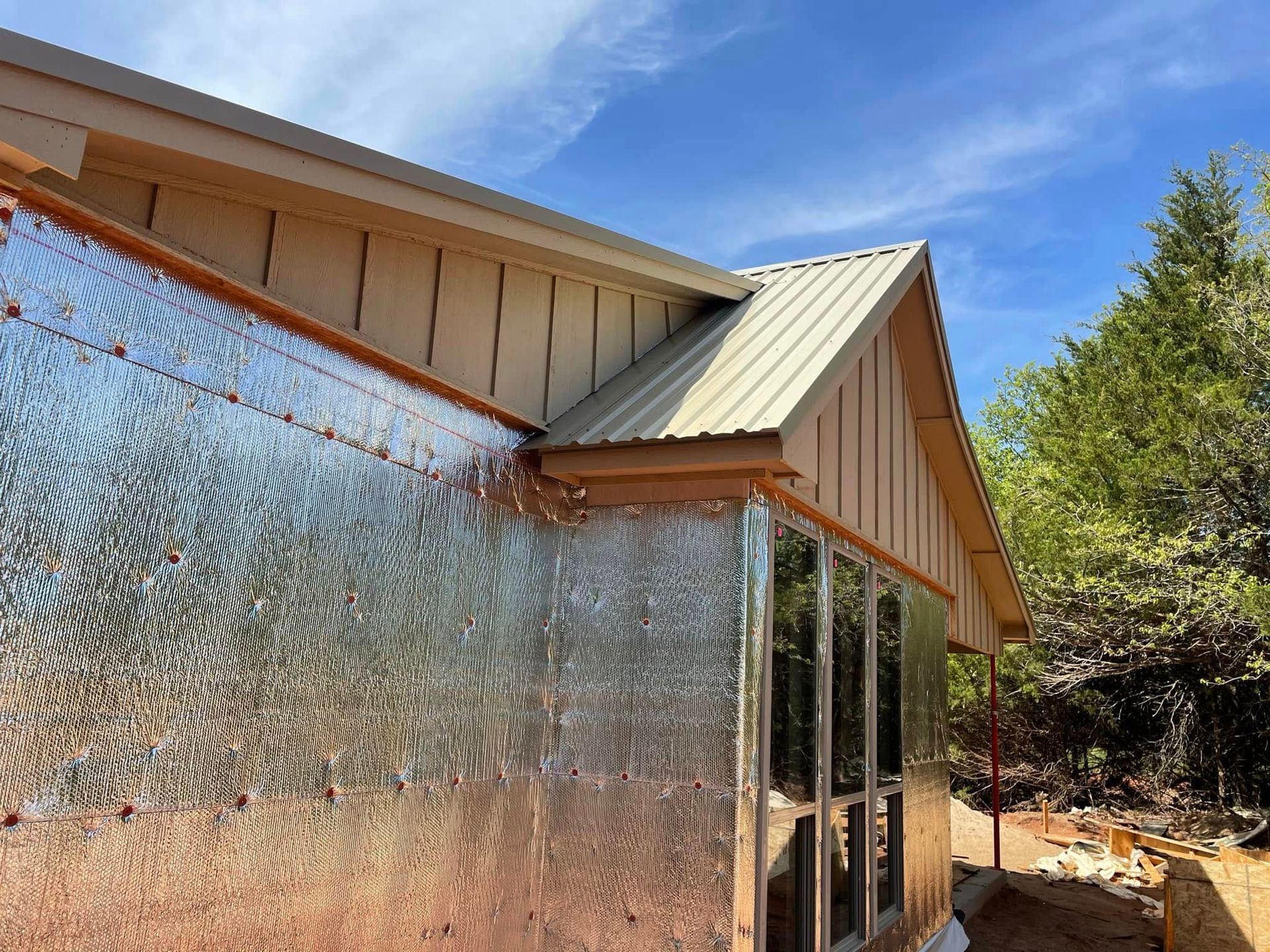 A house with a metal roof and a lot of windows is being built.