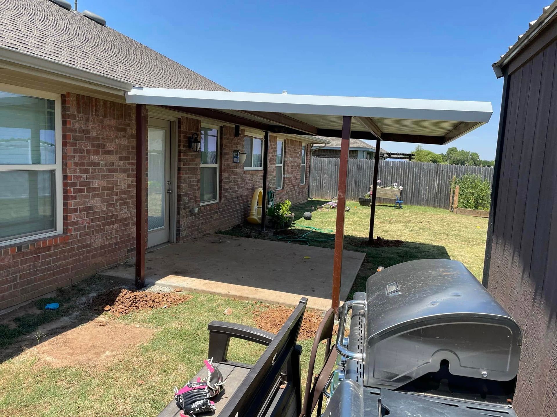 A brick house with a covered patio and a grill.