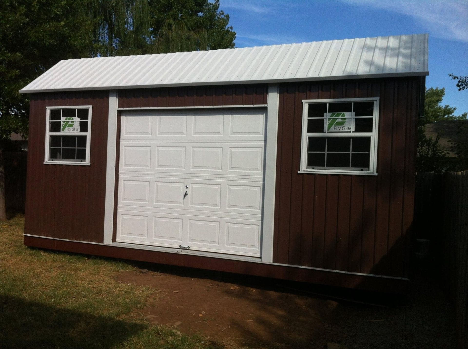 A brown shed with a white garage door and two windows