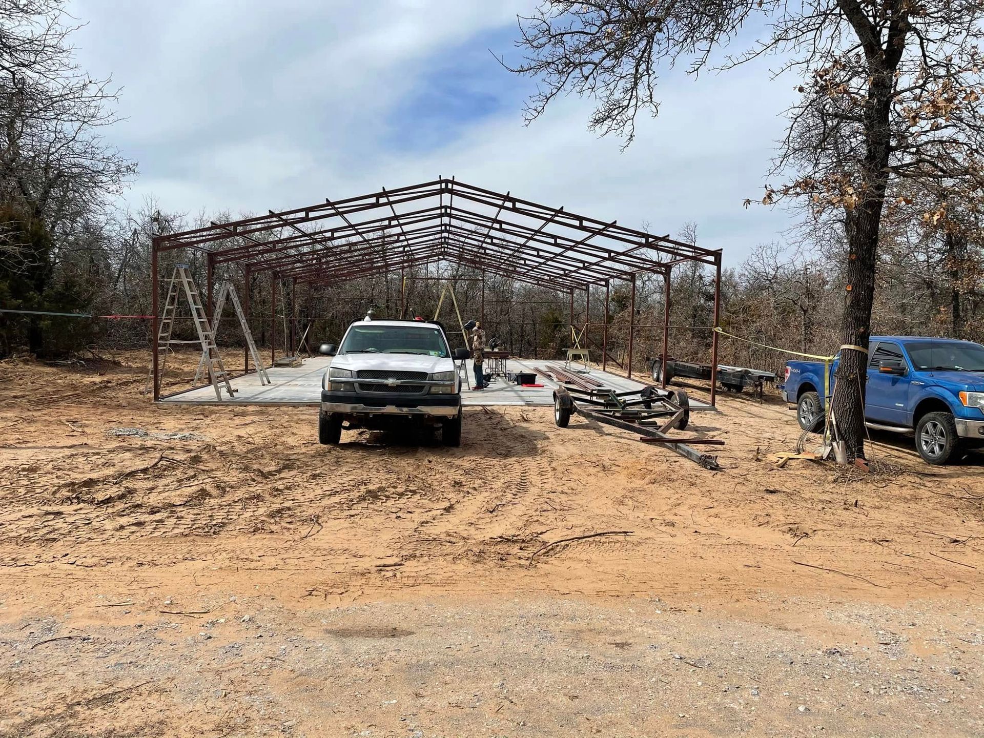 A white truck is parked in front of a metal structure under construction.