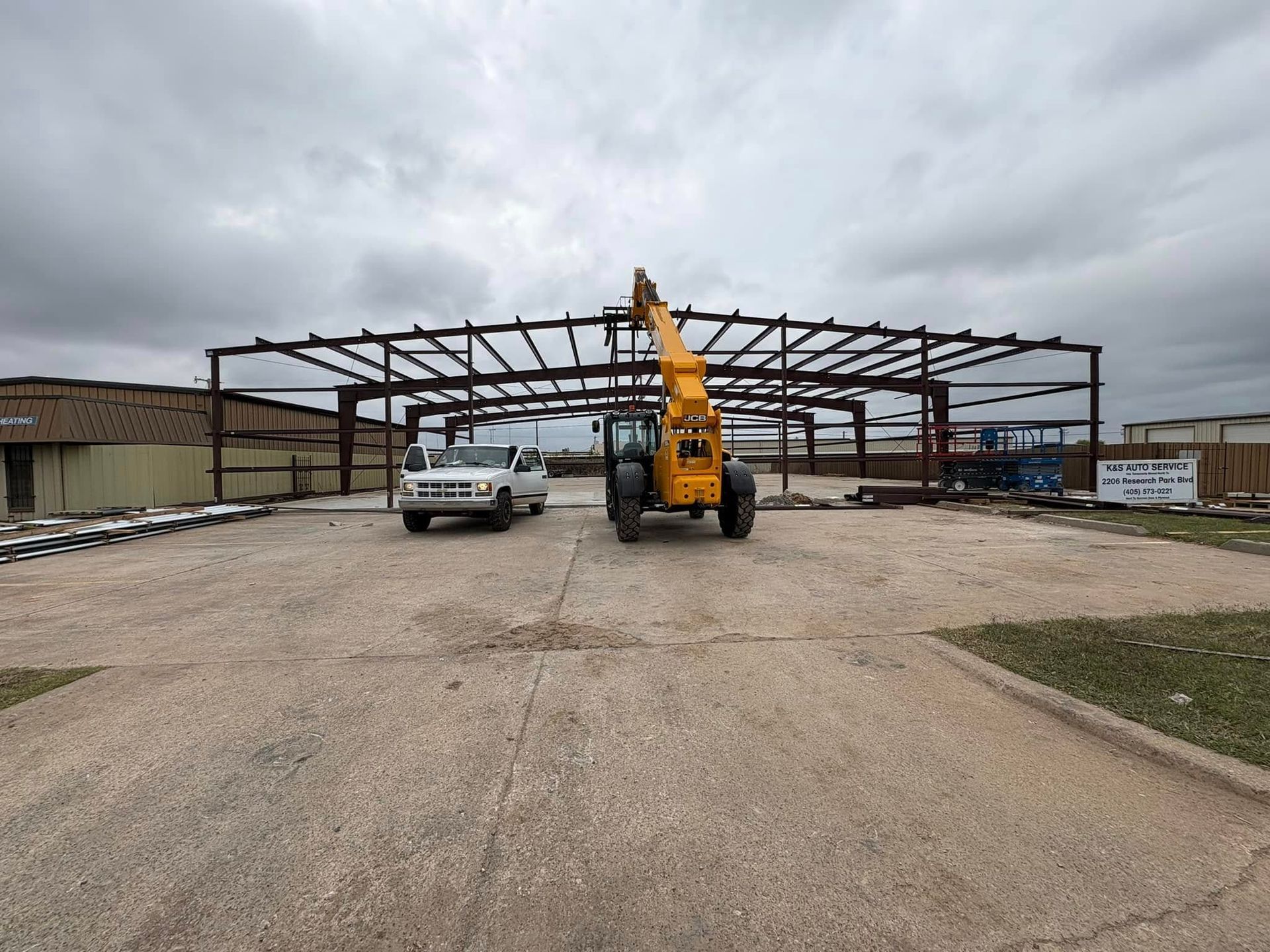 A truck and a crane are parked in front of a building under construction.