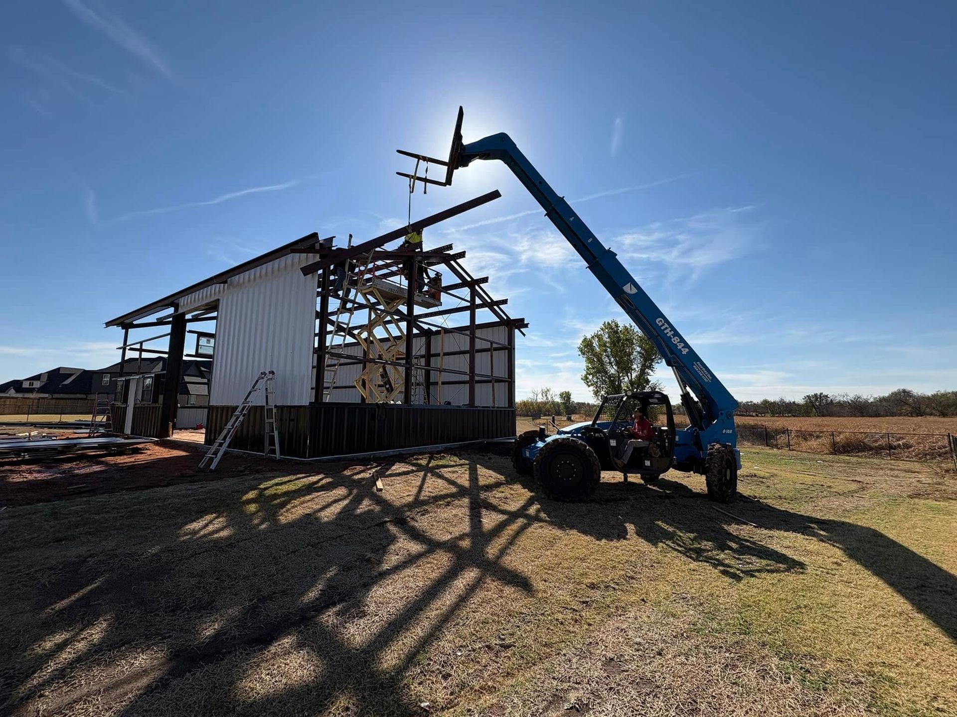 A forklift is lifting a piece of wood in front of a building under construction.
