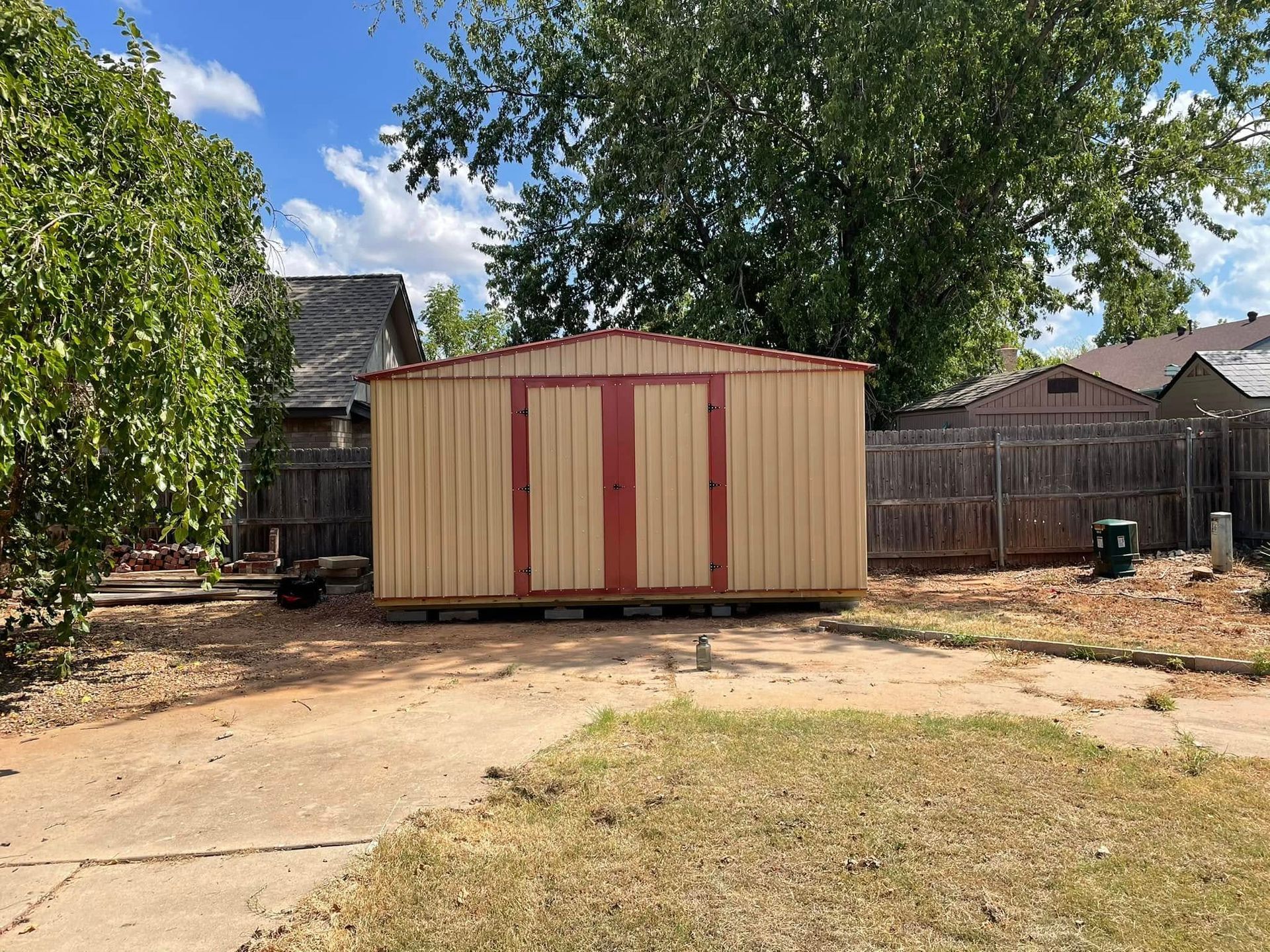 A small shed is sitting in the middle of a backyard next to a fence.