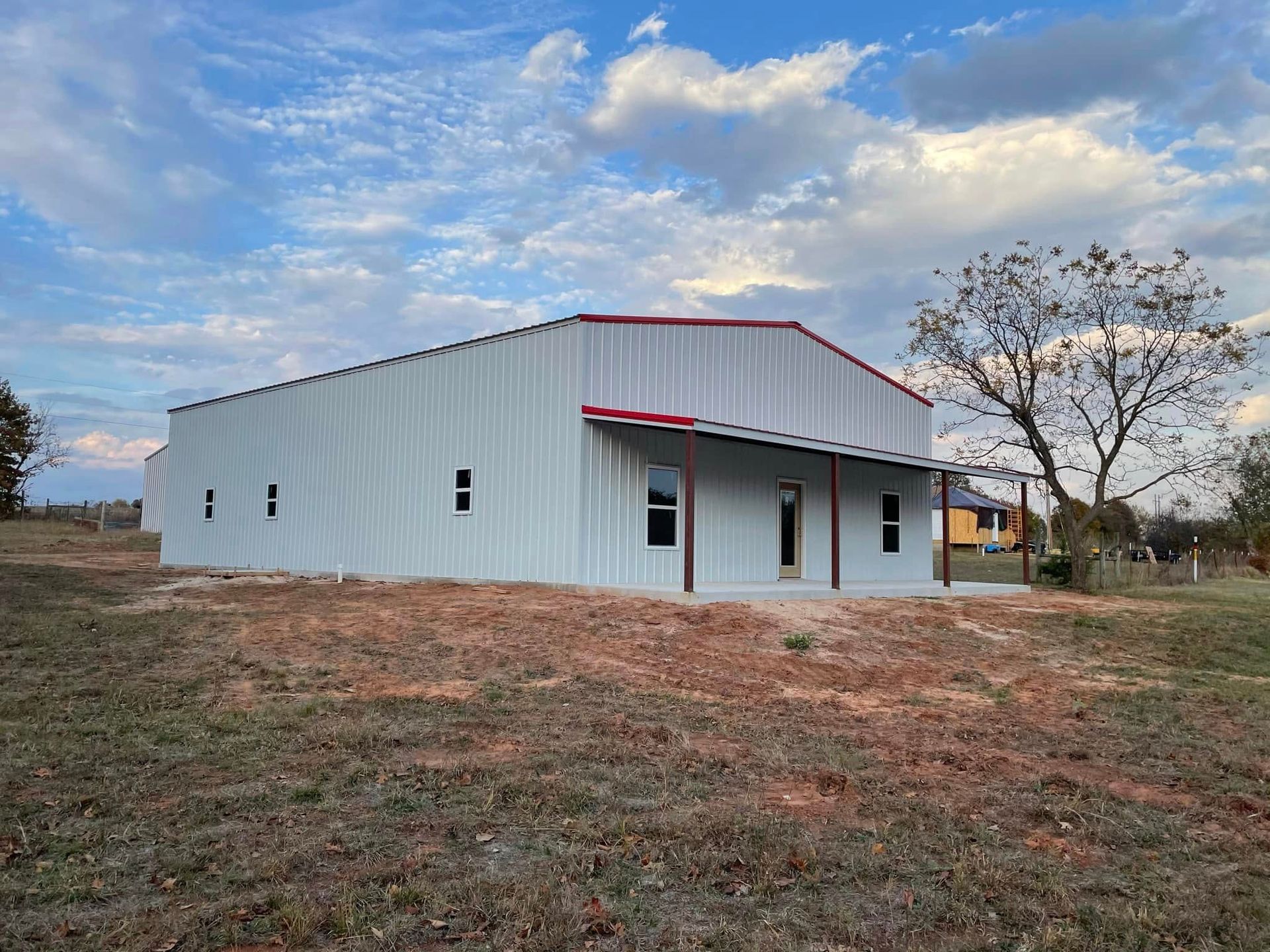 A large white building with a red roof is sitting in the middle of a field.