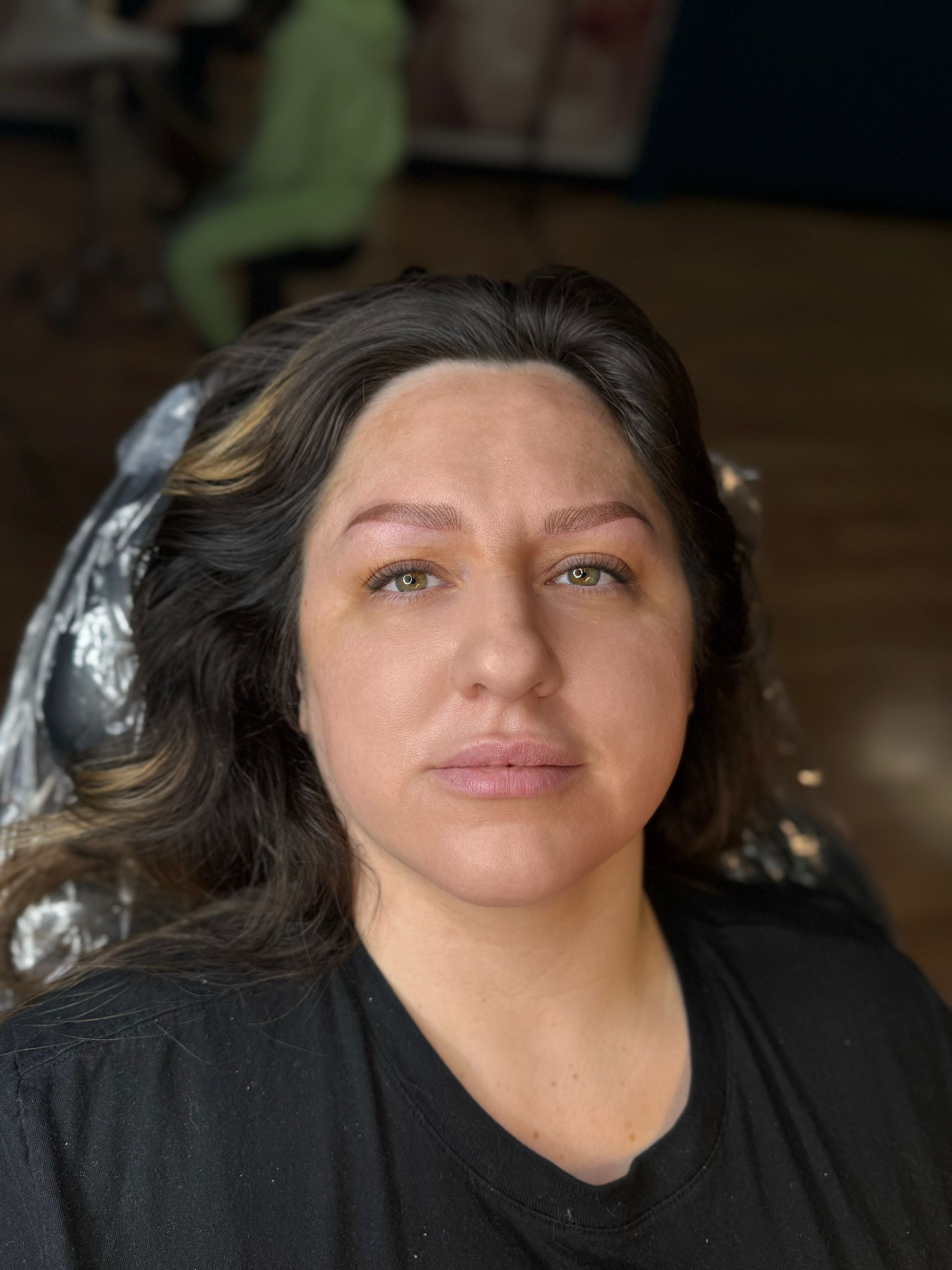 A woman is sitting in a chair with a black shirt on.