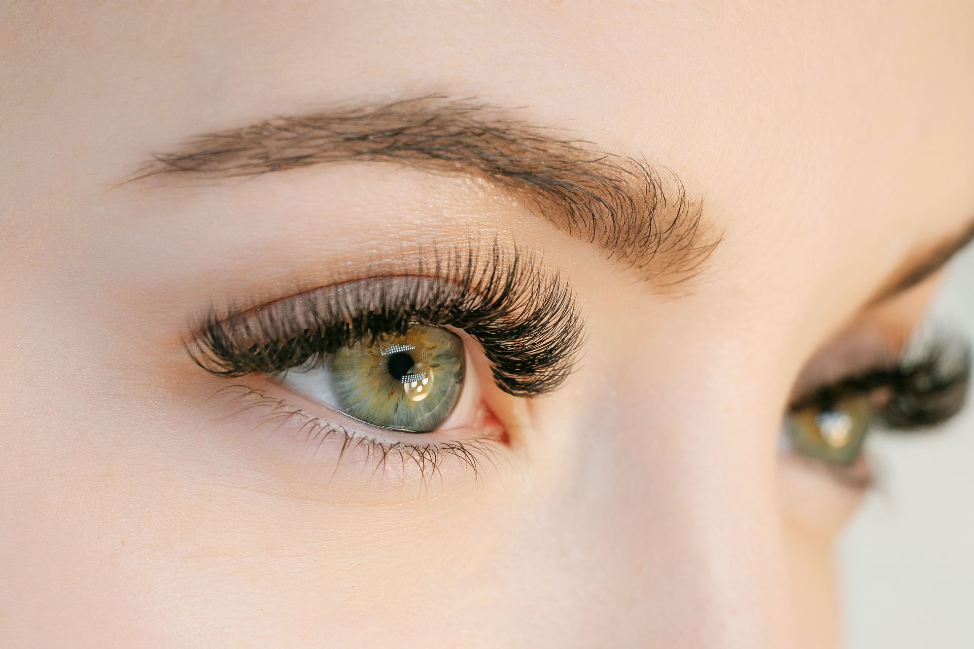 A close up of a woman 's green eye with long eyelashes.