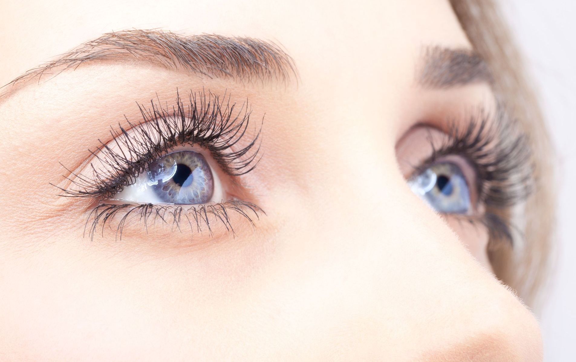 A close up of a woman 's blue eyes with long eyelashes.