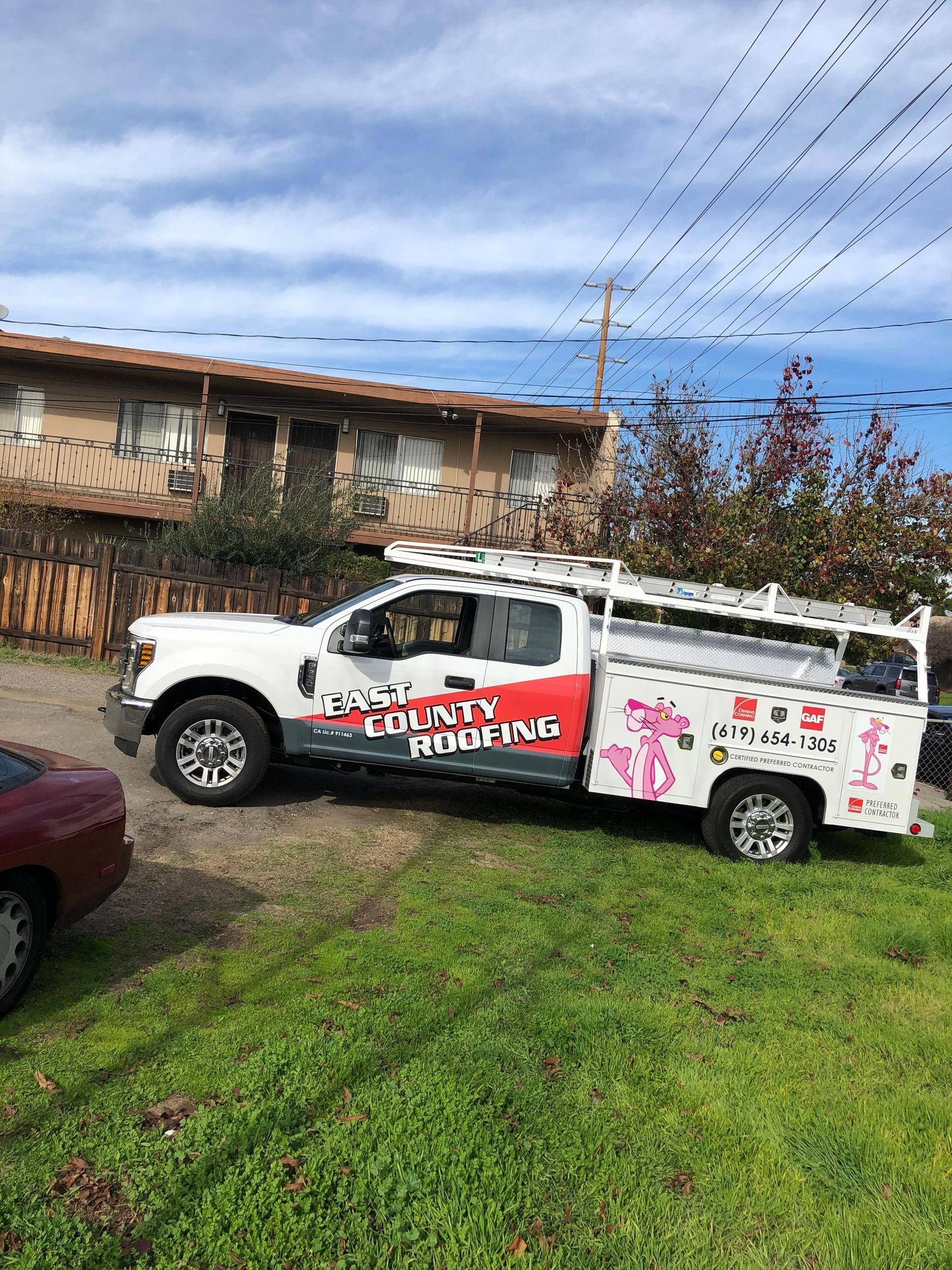 A pink panther truck is parked in front of a building.