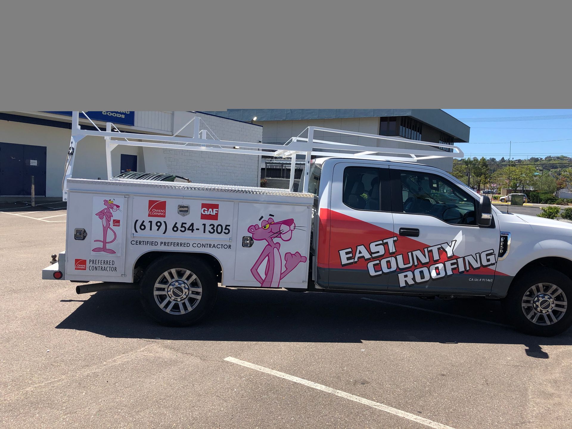A white truck with a pink panther on the side is parked in a parking lot.
