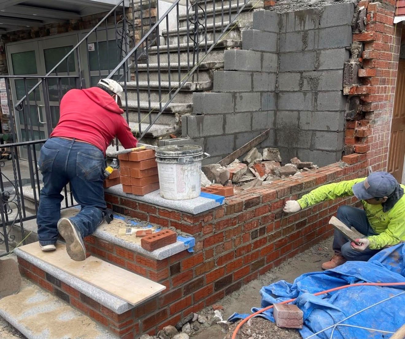 Construction workers laying brick on a stairway wall at a building site