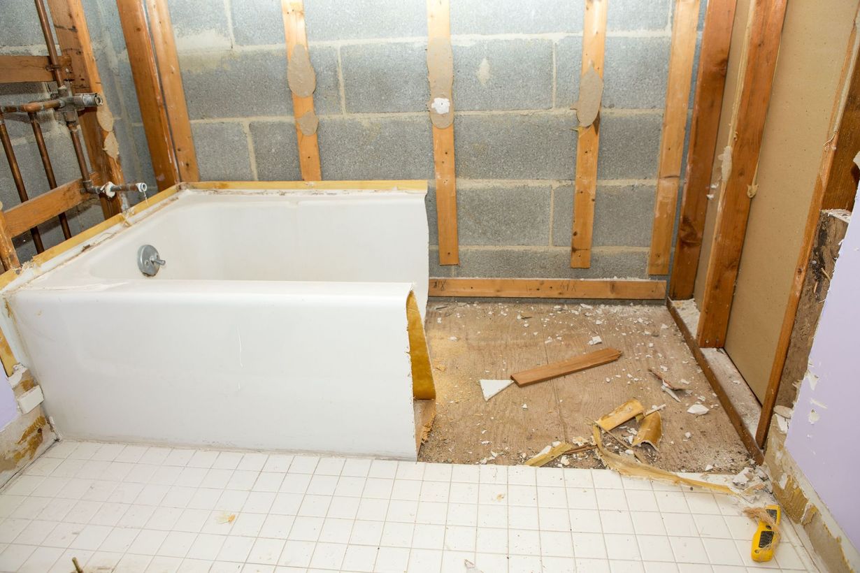 Bathroom under renovation with exposed studs, a tub, and debris on the floor