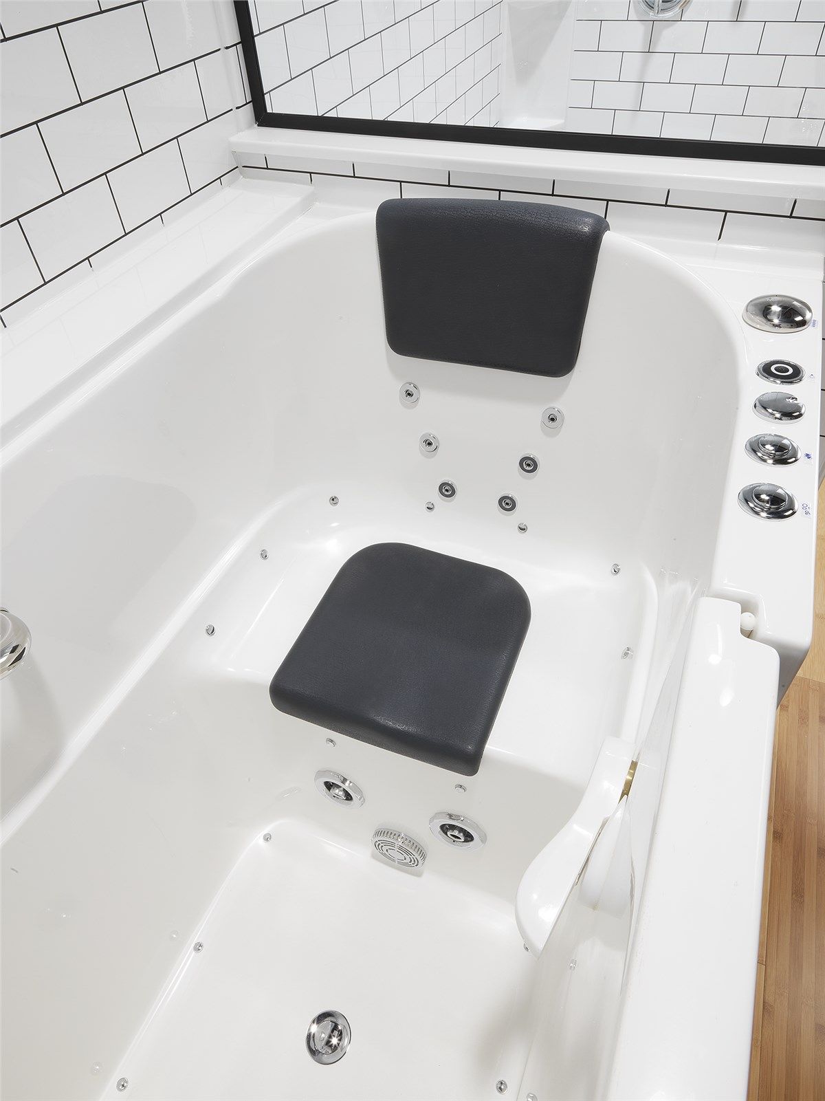 White jacuzzi tub with black headrest and seat, chrome jets, and white tile walls