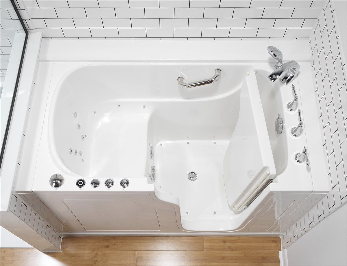 Walk-in bathtub with white tile surround and built-in grab bars beside a wood floor