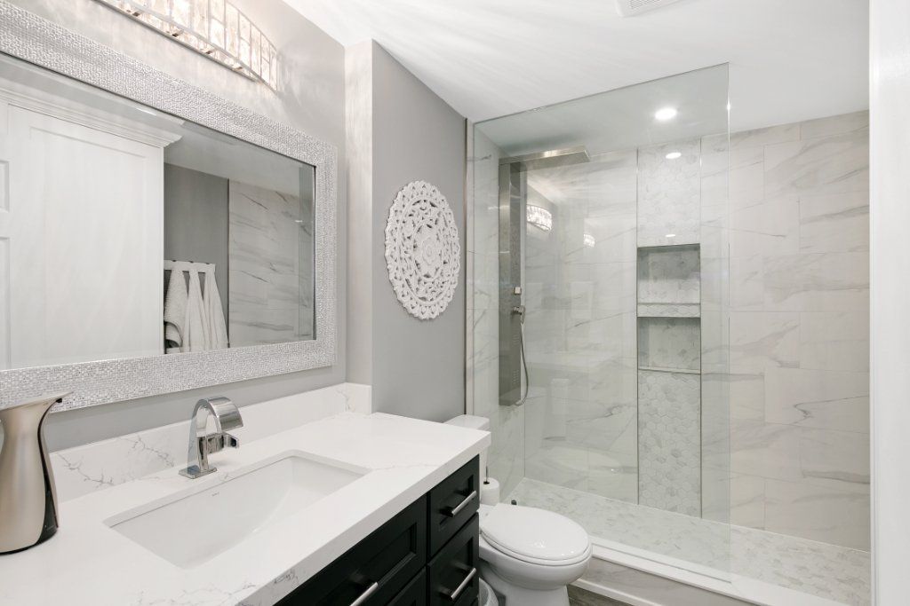 Modern white bathroom with vanity, large mirror, toilet, and glass-enclosed shower