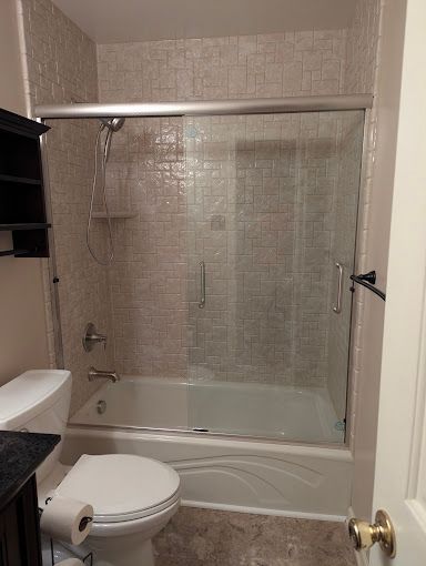 Small bathroom with a white toilet, sink, and tub with clear shower curtain.