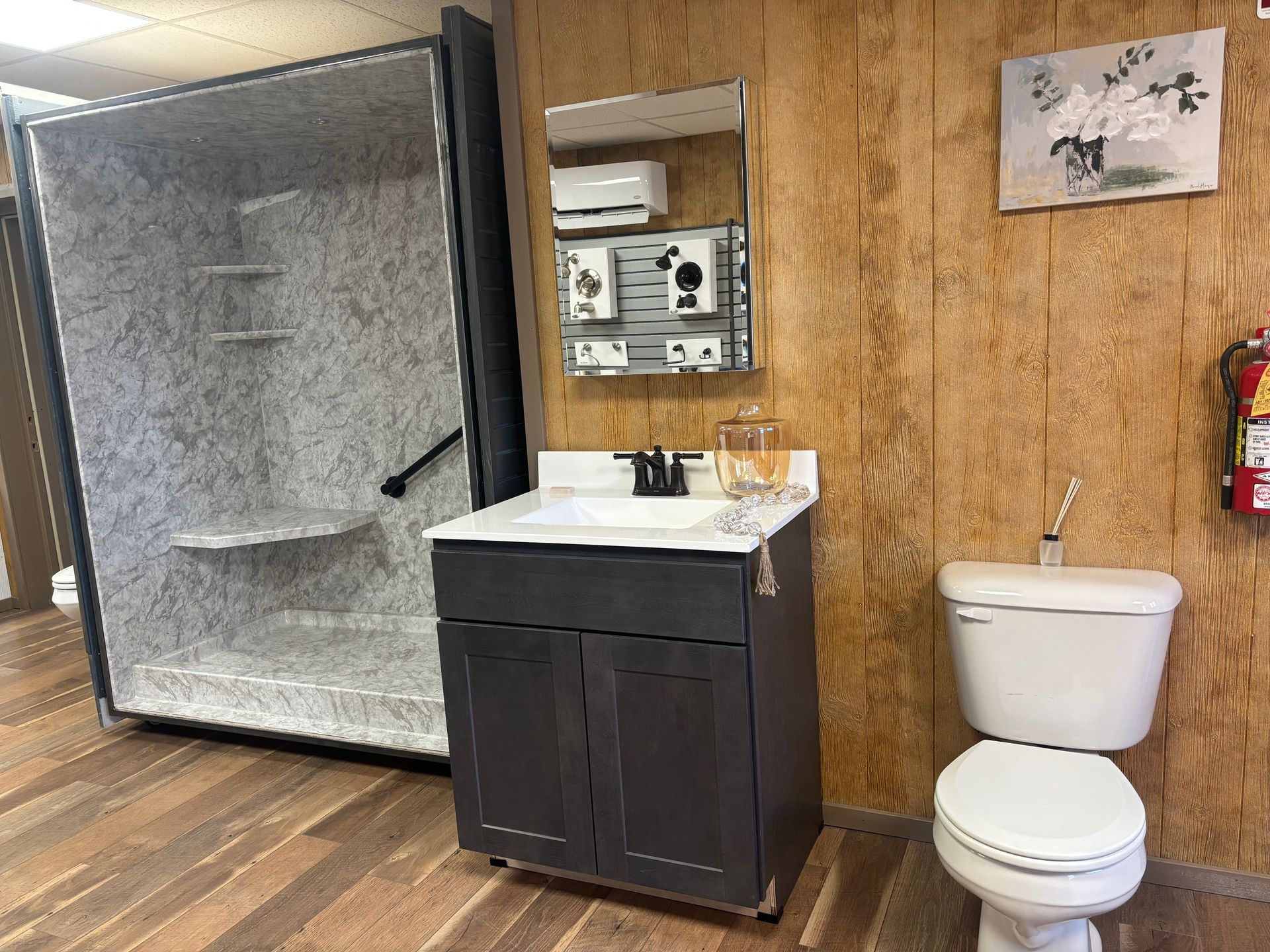 Bathroom with a sink, toilet, mirror, and tiled shower stall against wood-paneled walls