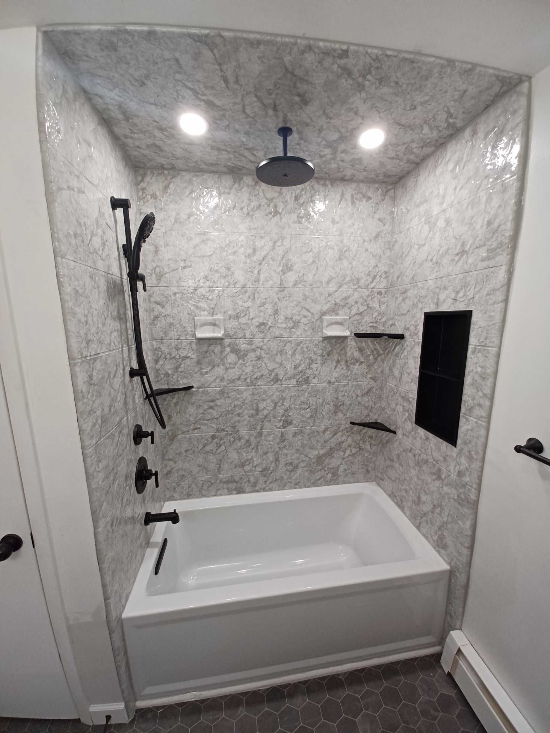 Accessible bathroom with walk-in tub, handheld shower, wall shelves, and recessed lights.
