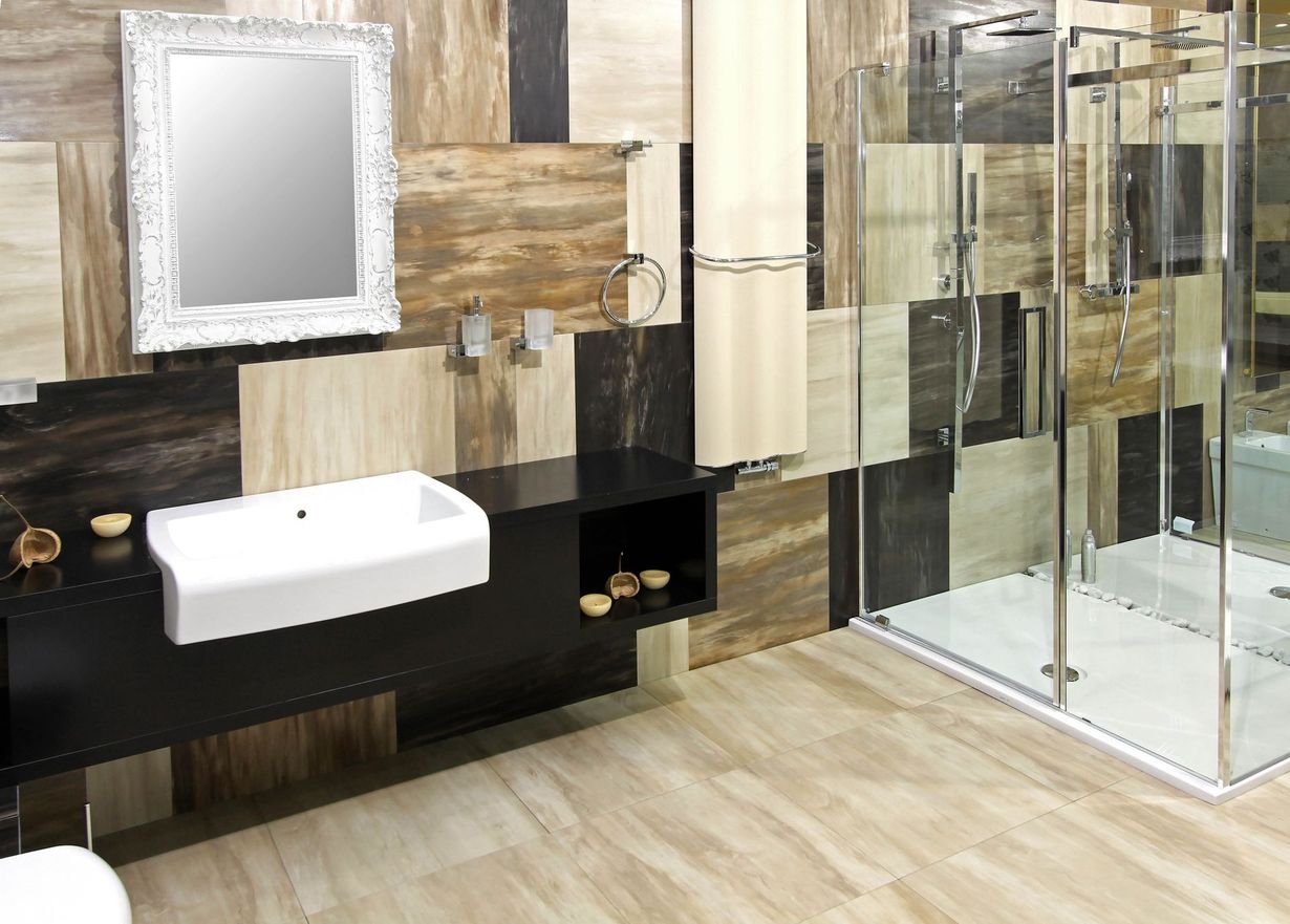 Modern bathroom with white sink, ornate mirror, wood accents, and glass shower enclosure