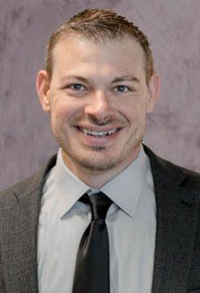 Smiling man in a suit and tie against a gray studio background
