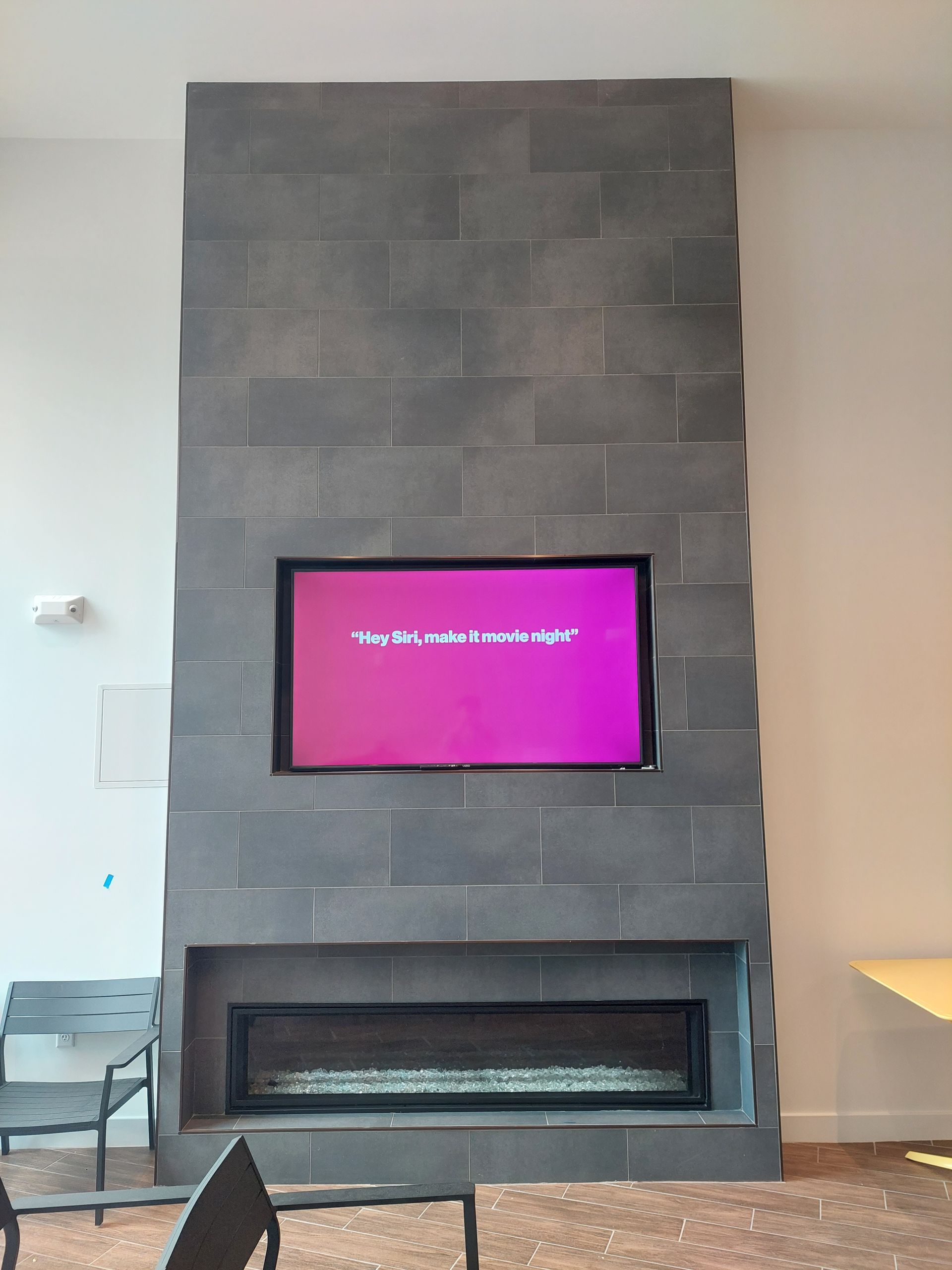 Gray stone fireplace with inset television and firebox, in a modern building.