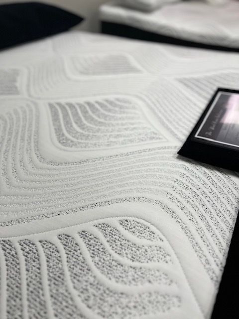 A white mattress is sitting on top of a bed next to a picture frame.