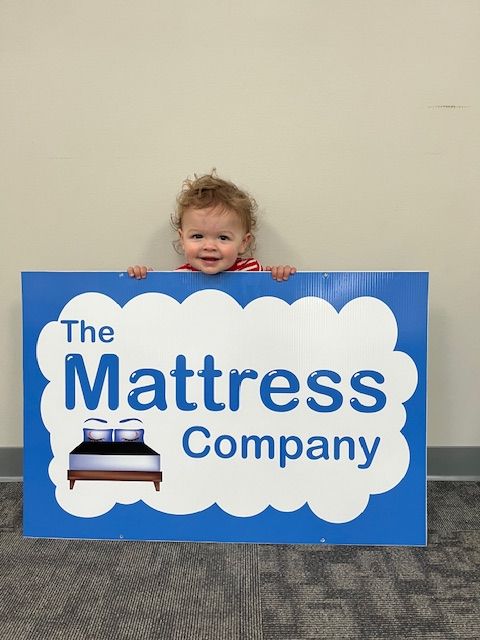 A little boy is holding a sign for the mattress company
