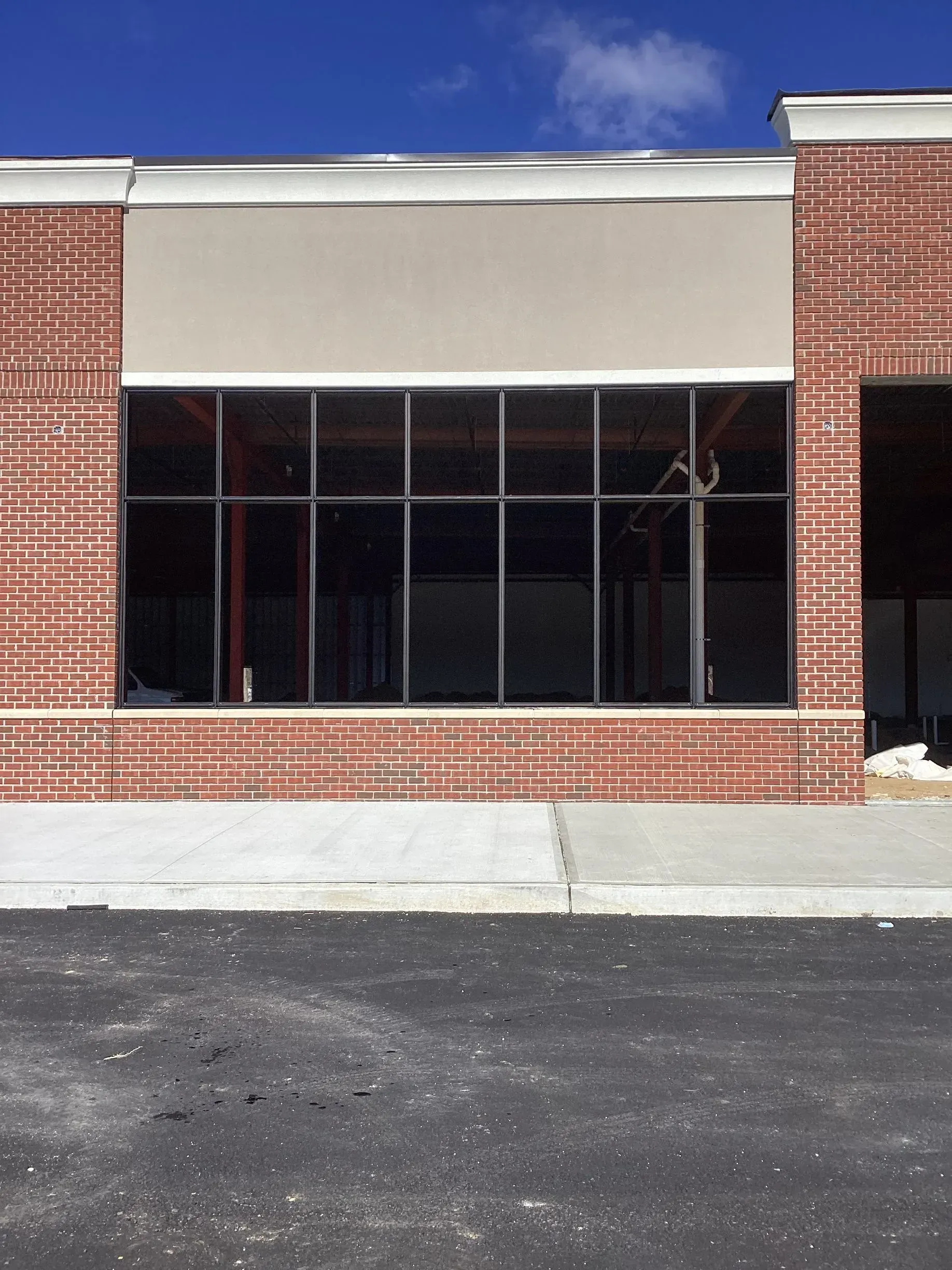 Building with large windows, brick exterior, gray awning, and blue sky.