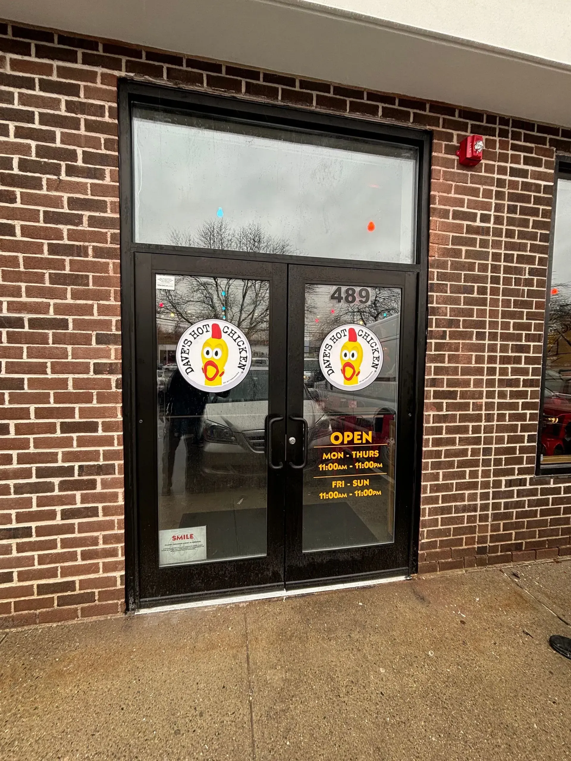 Double doors to a restaurant, with logos of a yellow hotdog with a chef's hat.