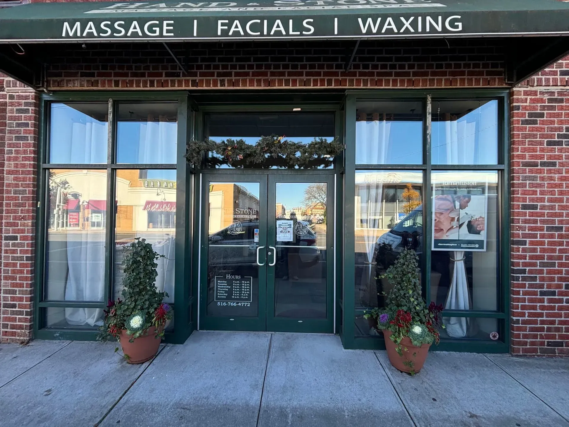 Exterior of a business with a green awning and double doors; services include massage, facials, and waxing.