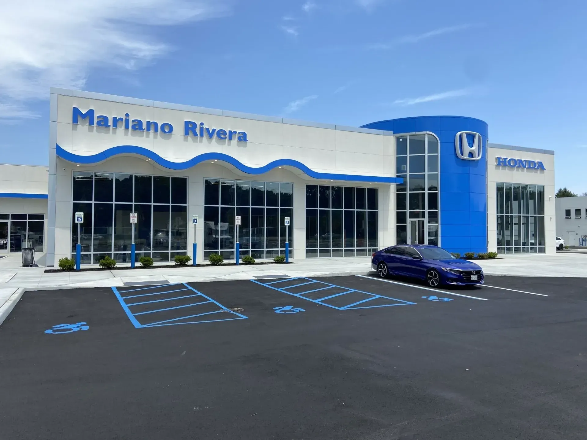 Mariano Rivera Honda dealership with a blue car in the parking lot under a blue sky.