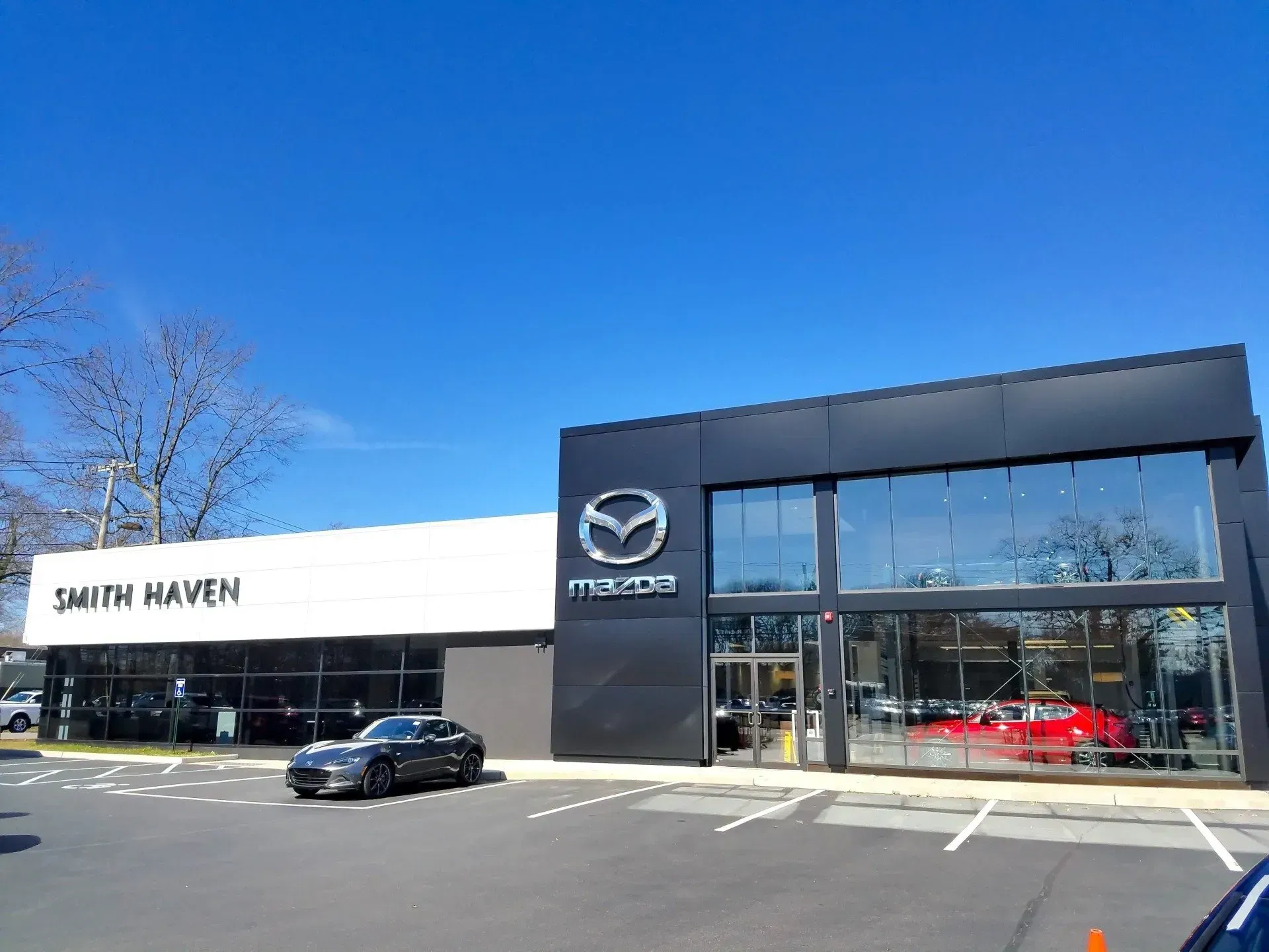 Smith Haven Mazda dealership with a black and white exterior, clear windows, and a car parked out front.