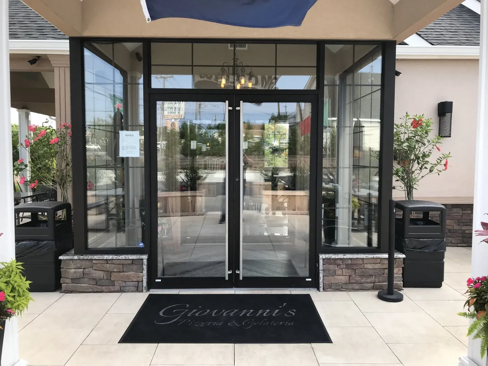 Restaurant entrance with glass doors, stone accents, and a welcome mat.