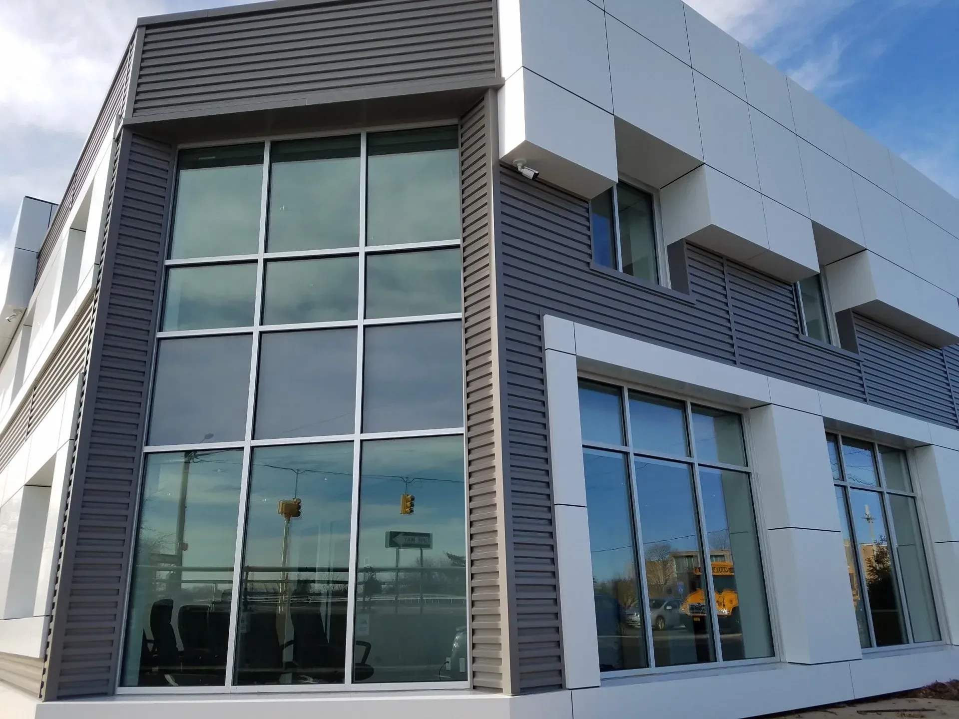 Modern building exterior with large windows, white and gray panels, and a blue sky.