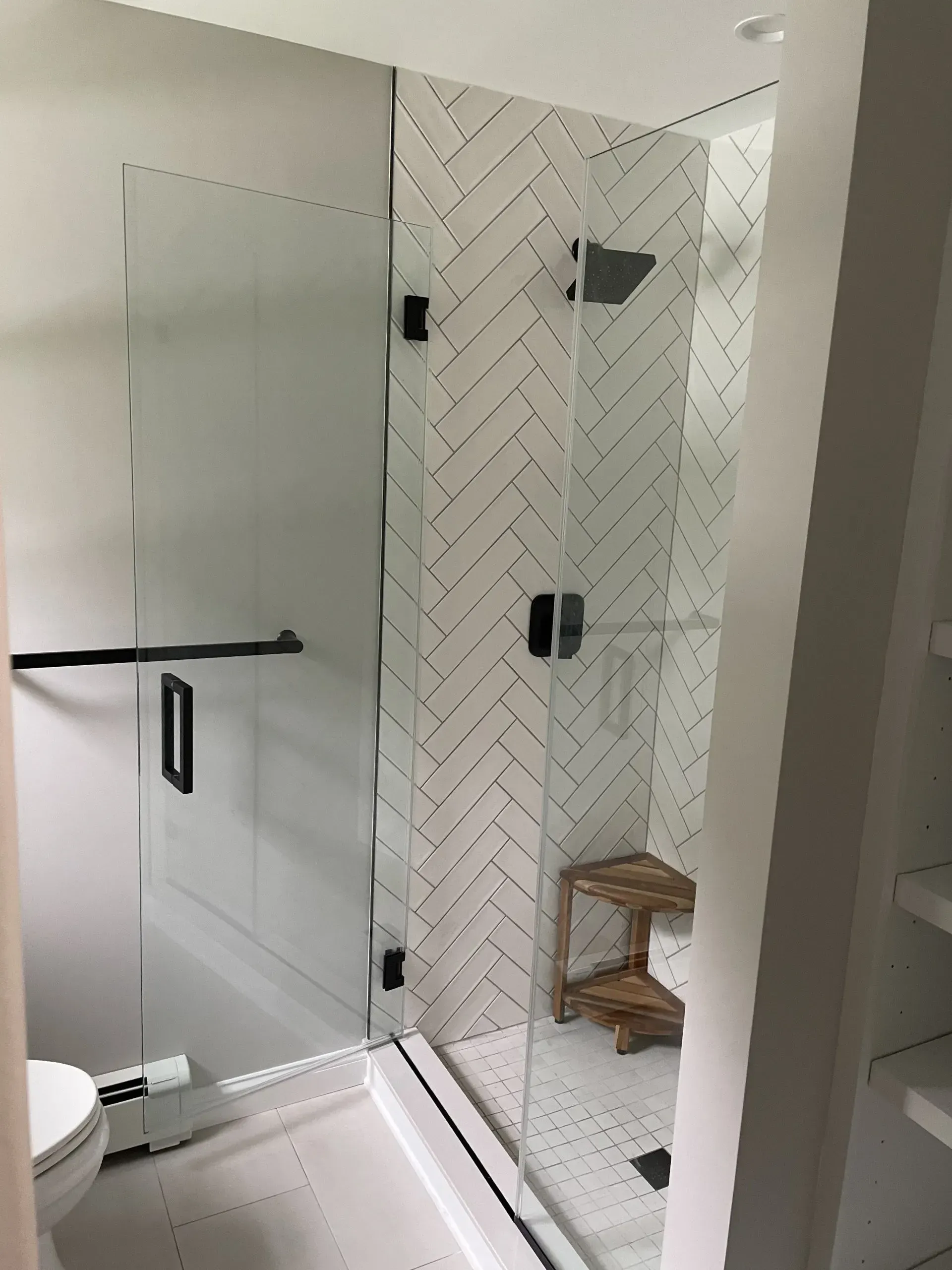 Glass shower enclosure with black fixtures and a patterned tile accent wall.