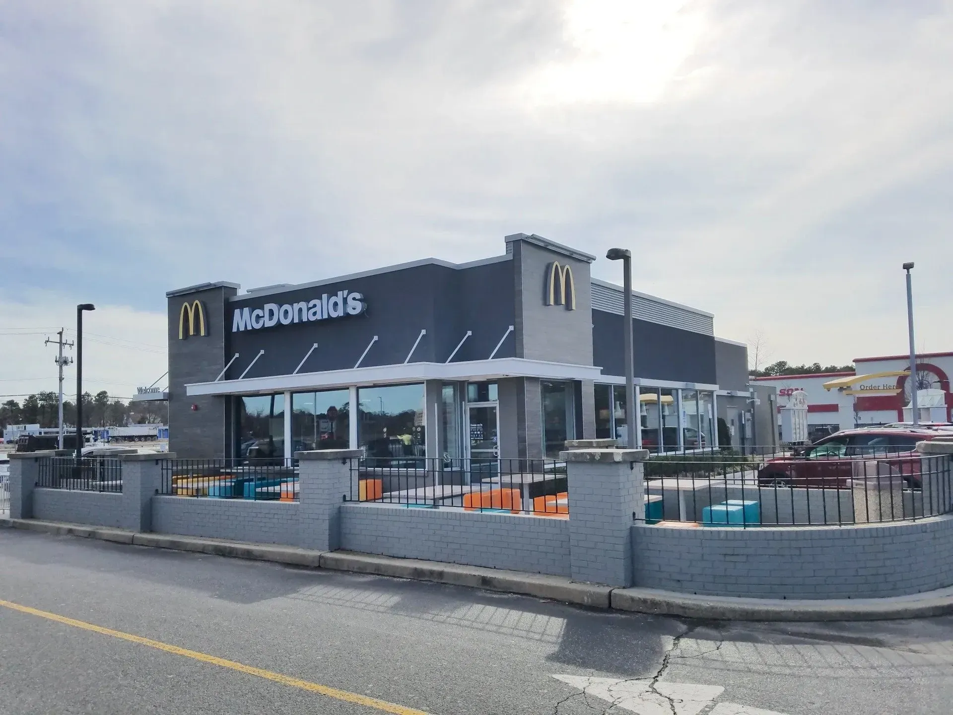 McDonald's restaurant with a modern design, gray and white exterior, under a partly cloudy sky.